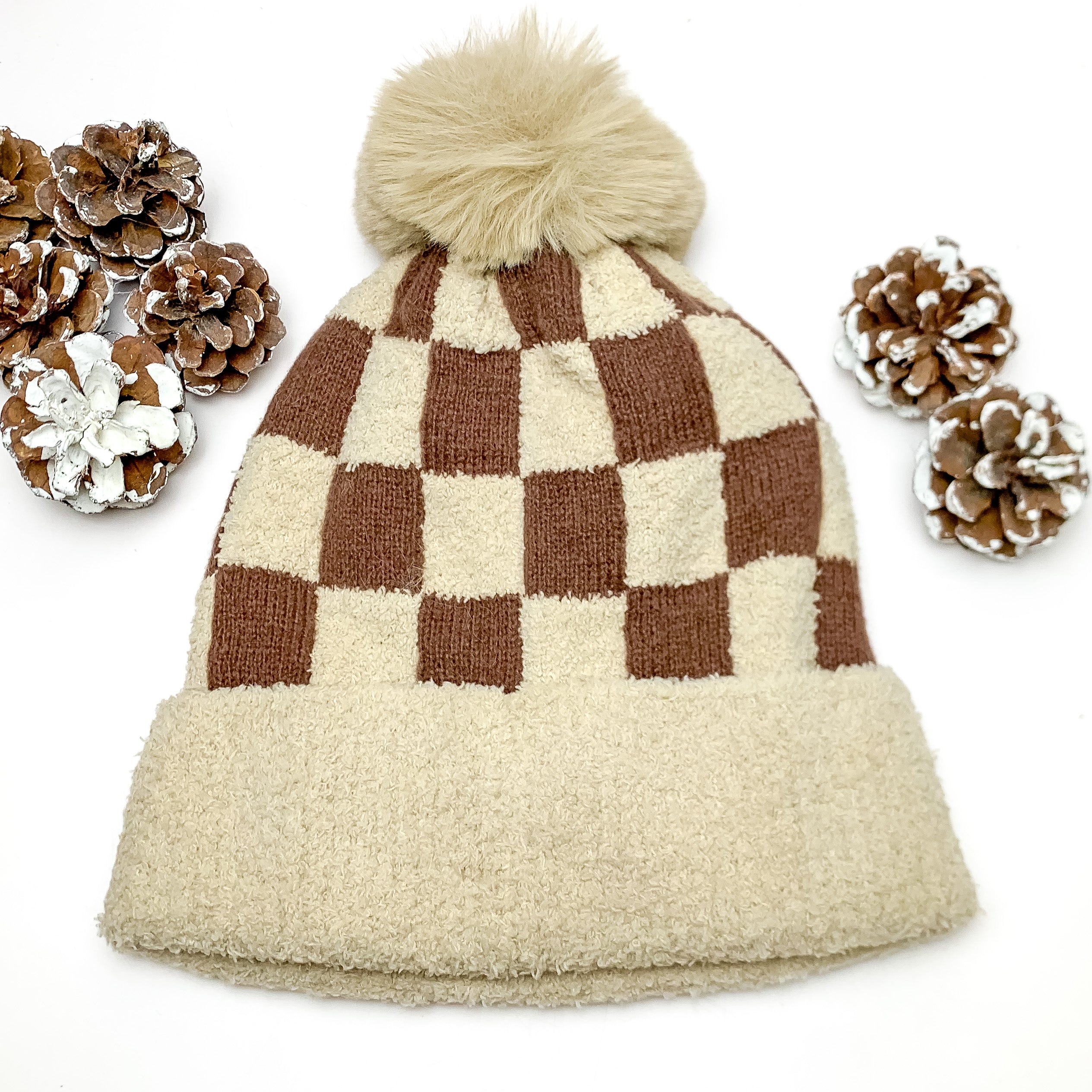 Checkered Beanie in Beige and Brown. This beanie is pictured on a white background with pinecones around it. 