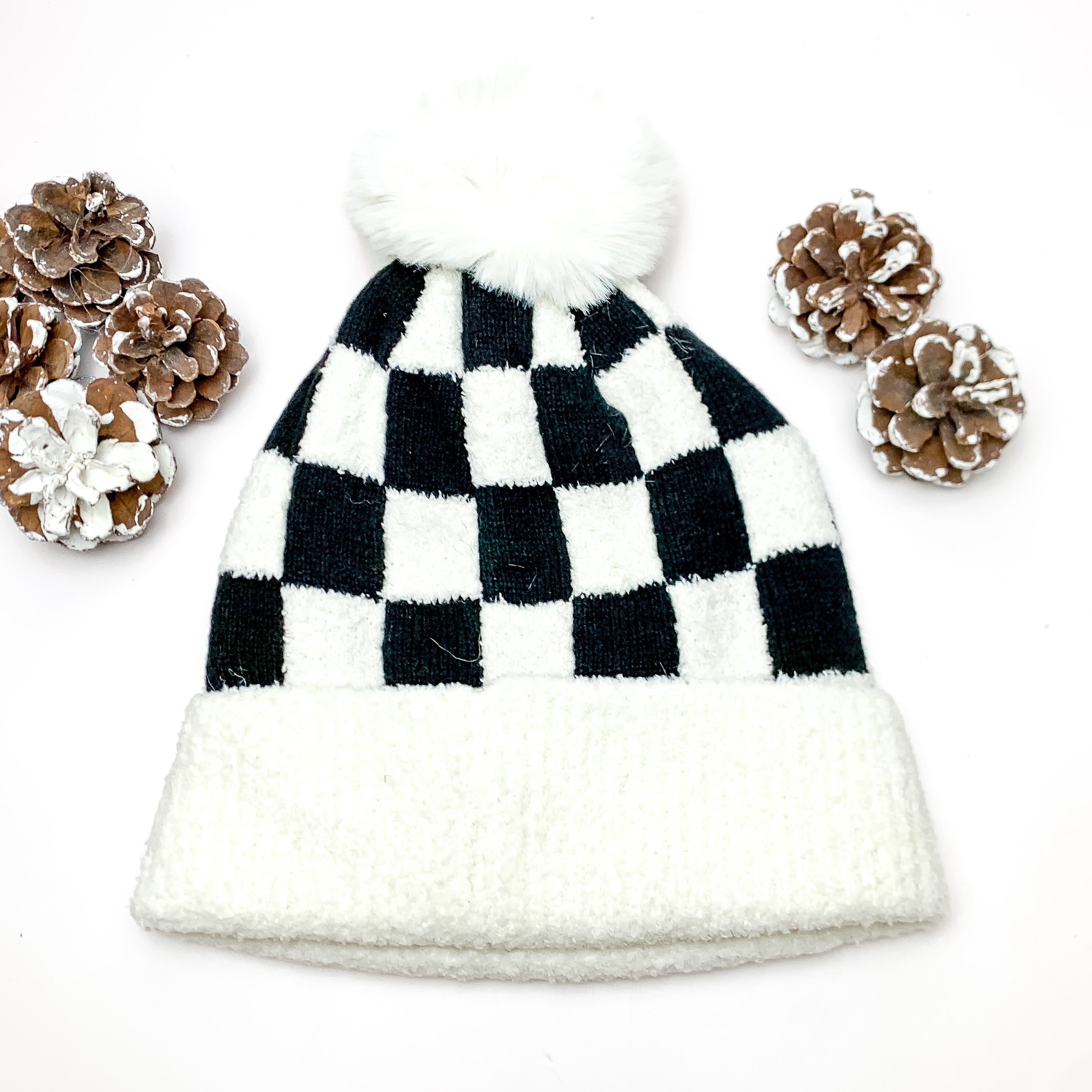 Checkered Beanie in White and Black. This beanie is pictured on a white background with pinecones around it.