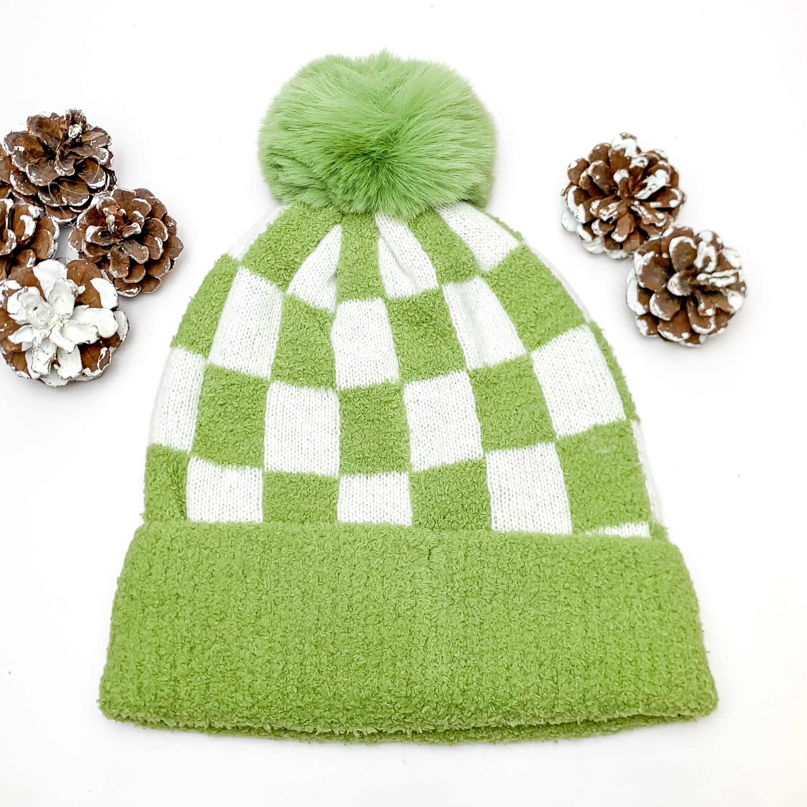 Checkered Beanie in Olive Green and White. This beanie is pictured on a white background with pinecones around it.