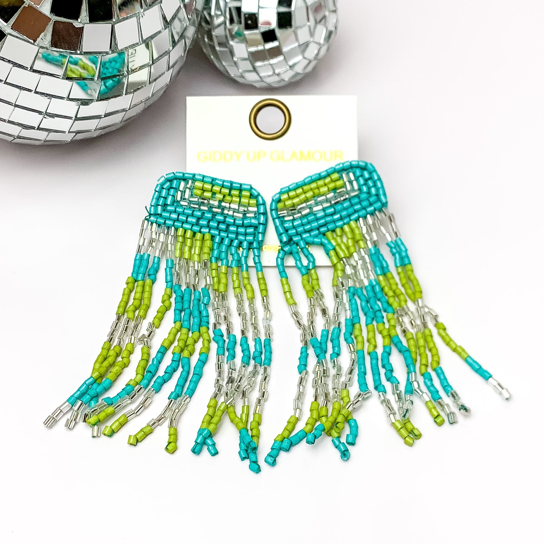 Beaded Tassel Earrings in Blue, and Green. Pictured on a white background with disco balls in the top left corner. 
