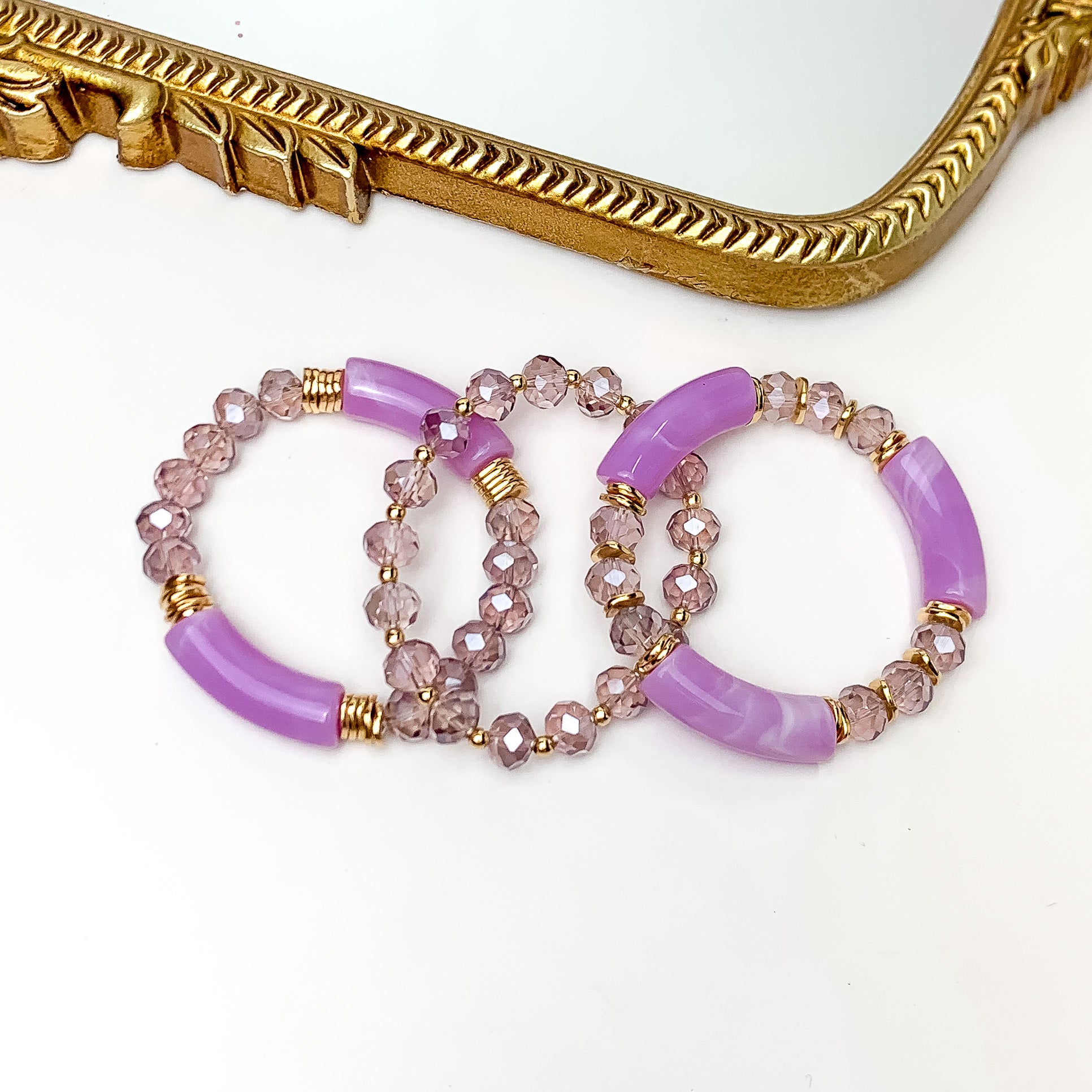 Set of Three | Sunny Bliss Crystal Beaded Bracelet Set in Purple. Pictured on a white background with a gold trim mirror above the bracelets.