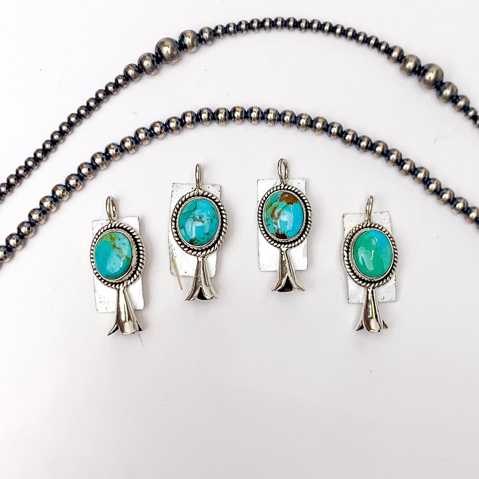 In the picture are handmade circle pendants that include genuine sterling silver and genuine kingman turquoise stones with a white background