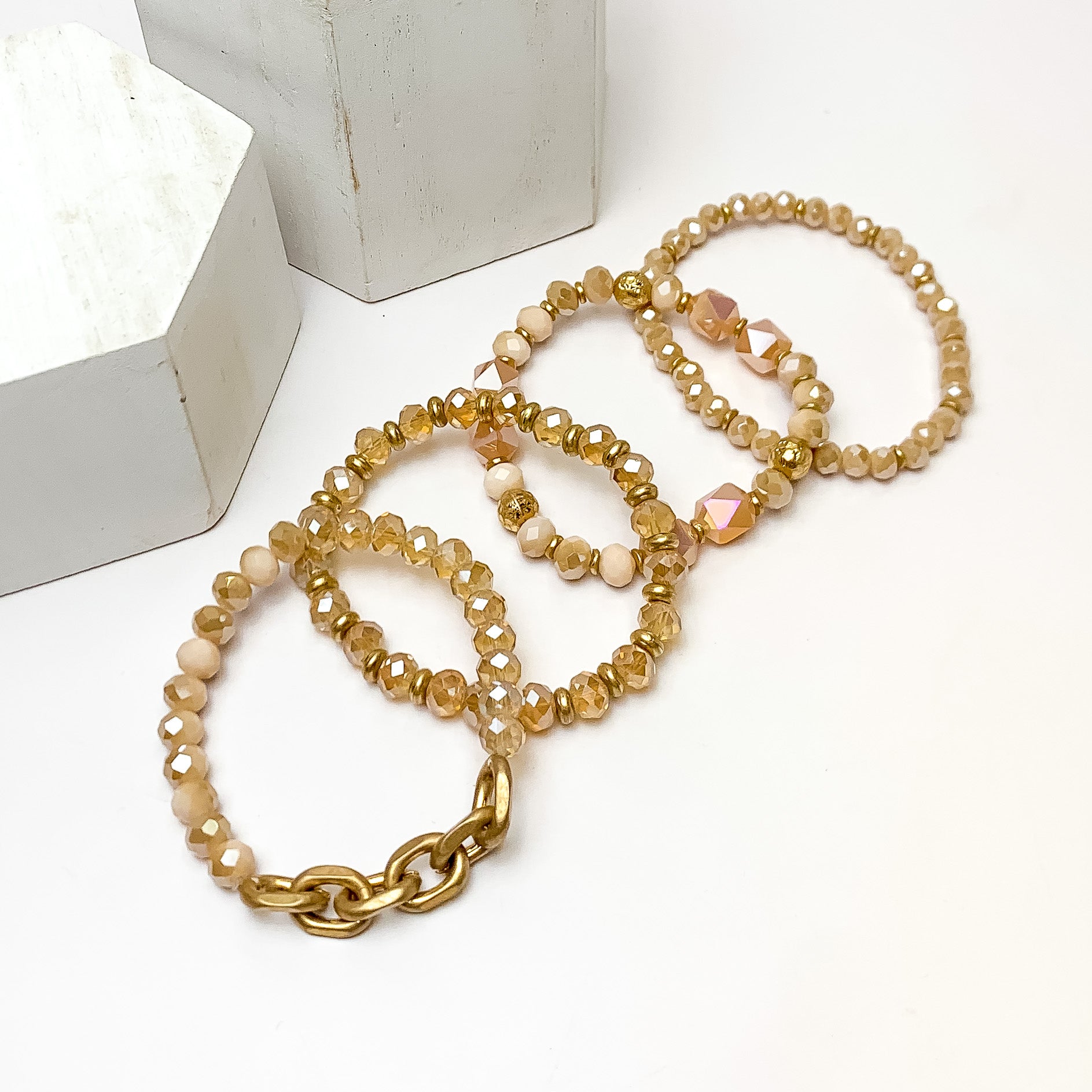 Set of Four | Upper East Gold Tone Beaded Bracelet Set in Blush Pink. Pictured on a white background with two white podium behind the earrings.