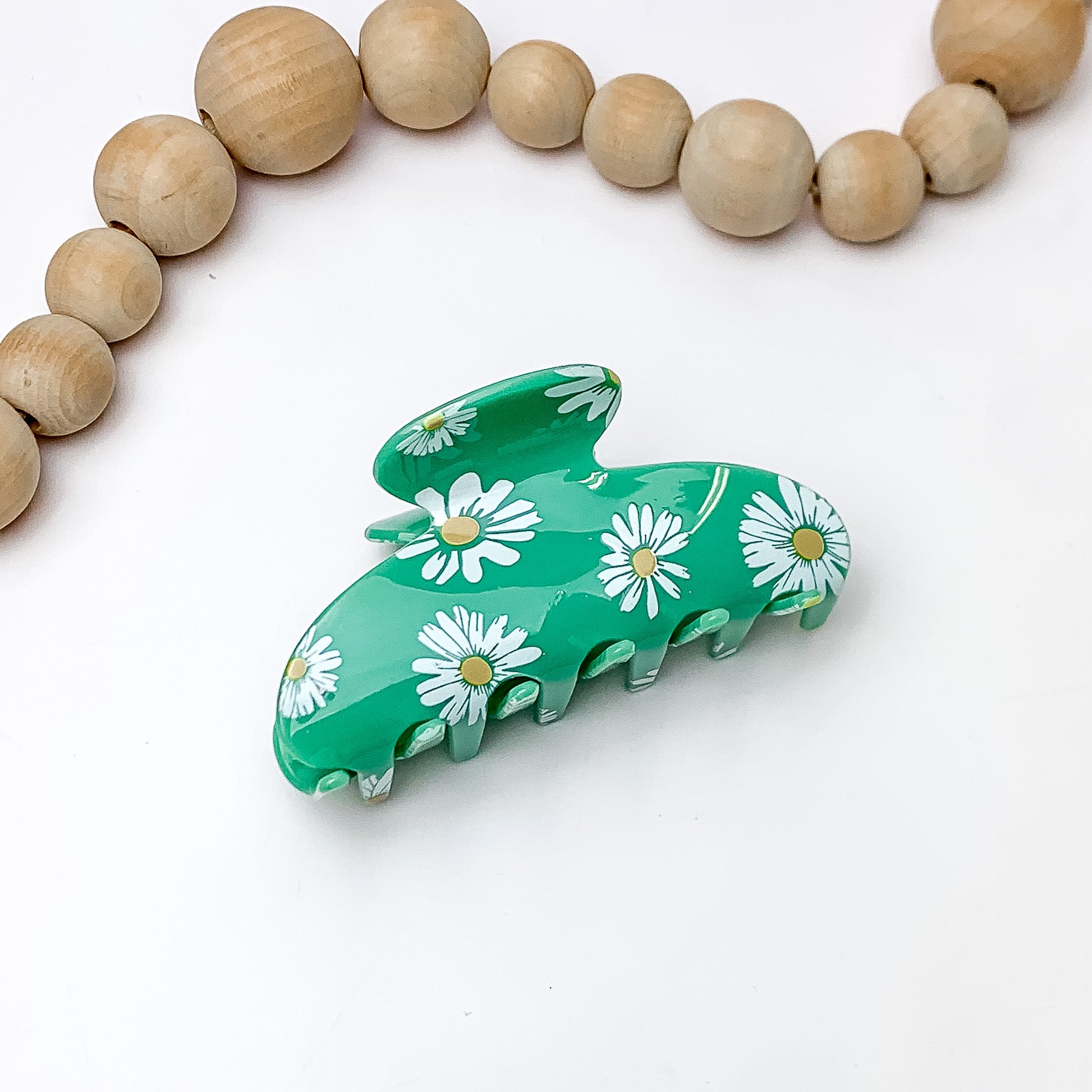 Flower Fields Hair Clip in Sage Green. Pictured on a white background with wood beads above the hair clip.