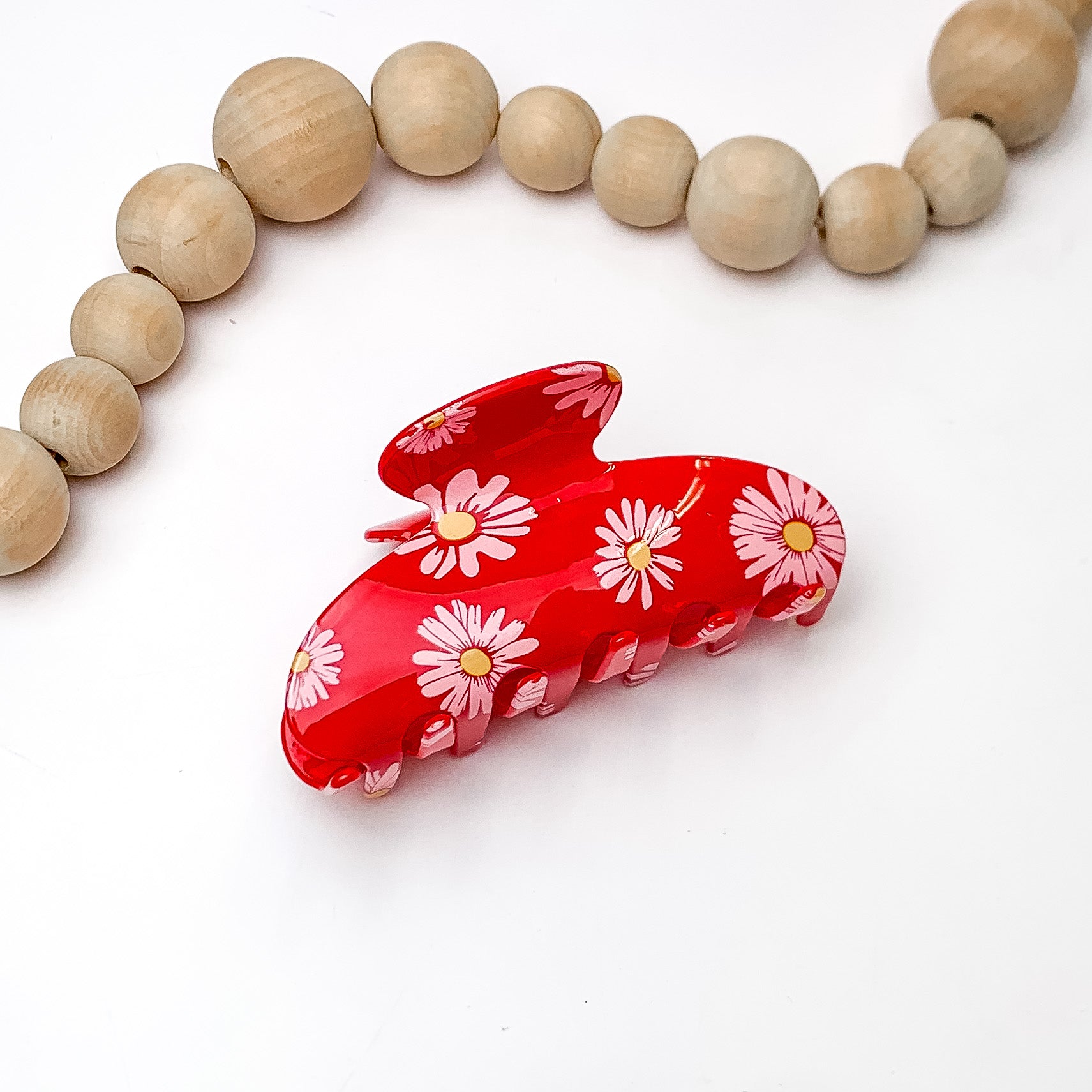Flower Fields Hair Clip in Red. Pictured on a white background with wood beads above the hair clip.