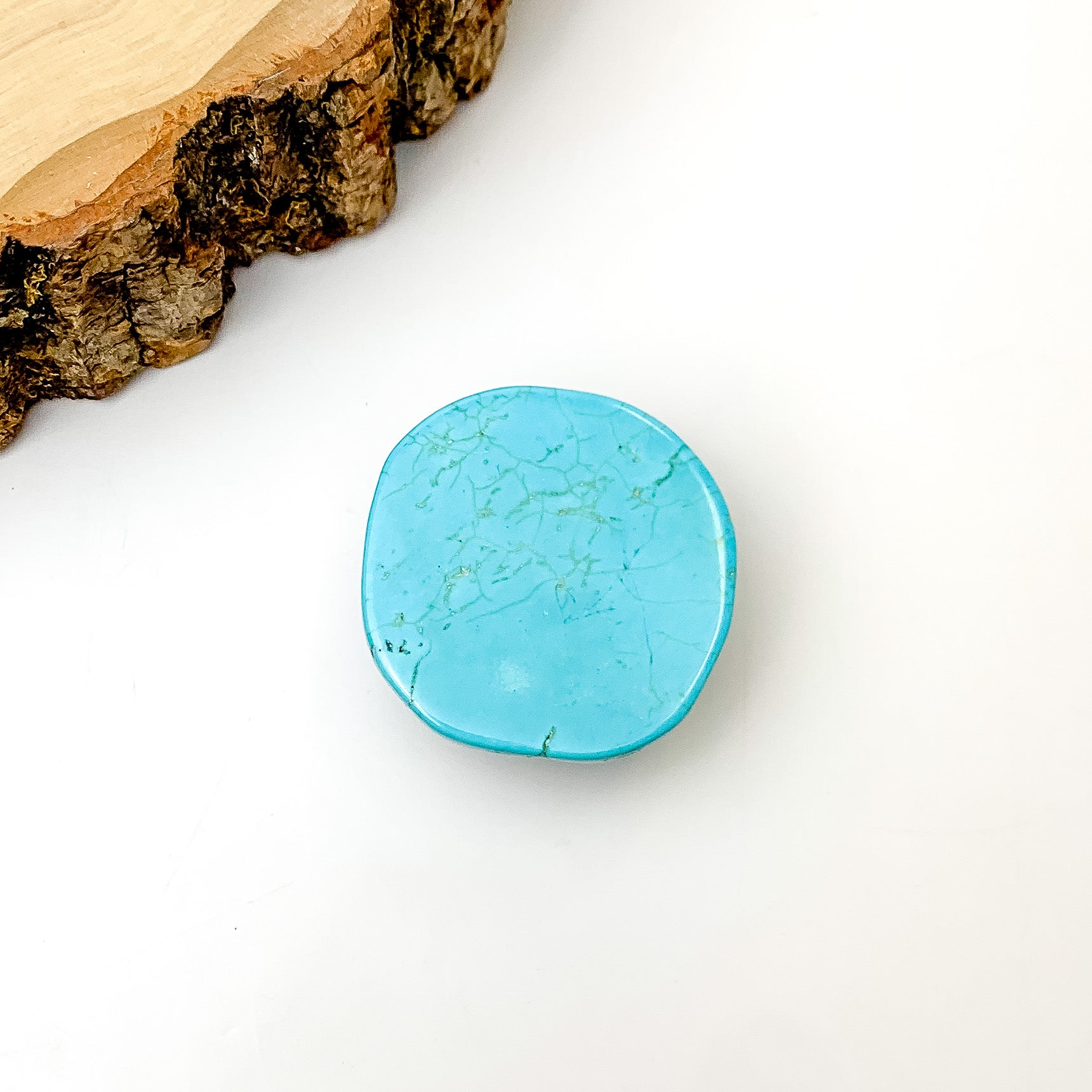 Turquoise Slab Circular Phone Grip. Pictured on a white background with a wood piece in the top left corner.