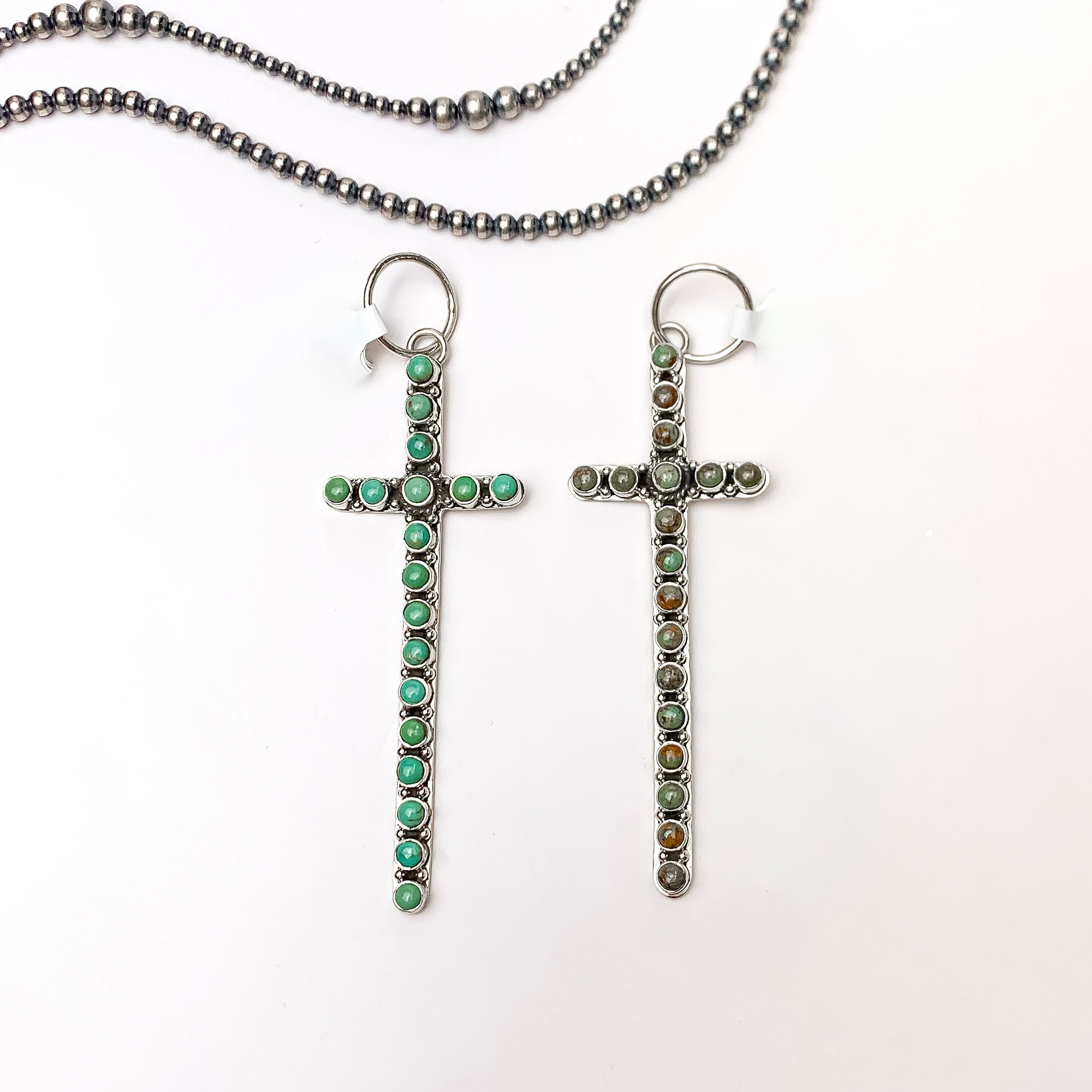 In the picture are sterling silver cross pendants in a kingman turquoise color with a white background