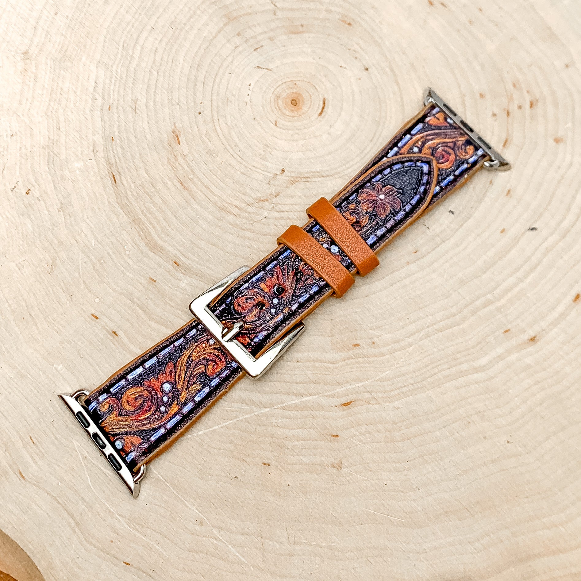 Brown Faux Leather Watch Band With Desert Design. pictured on a wood piece background.
