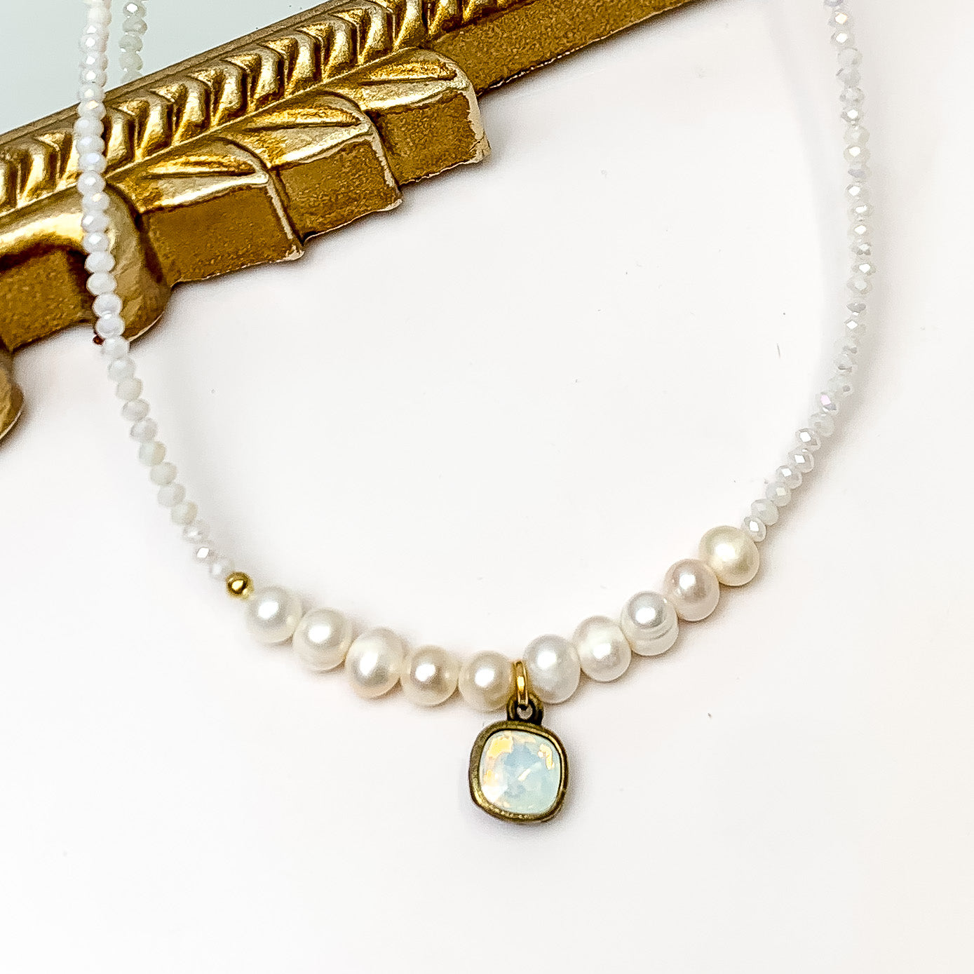 Pink Panache White Crystal and Pearl Beaded Necklace With Bronze/ White Opal Cushion Cut. Pictured on a white background with the top of the necklace against a mirror with a gold frame.