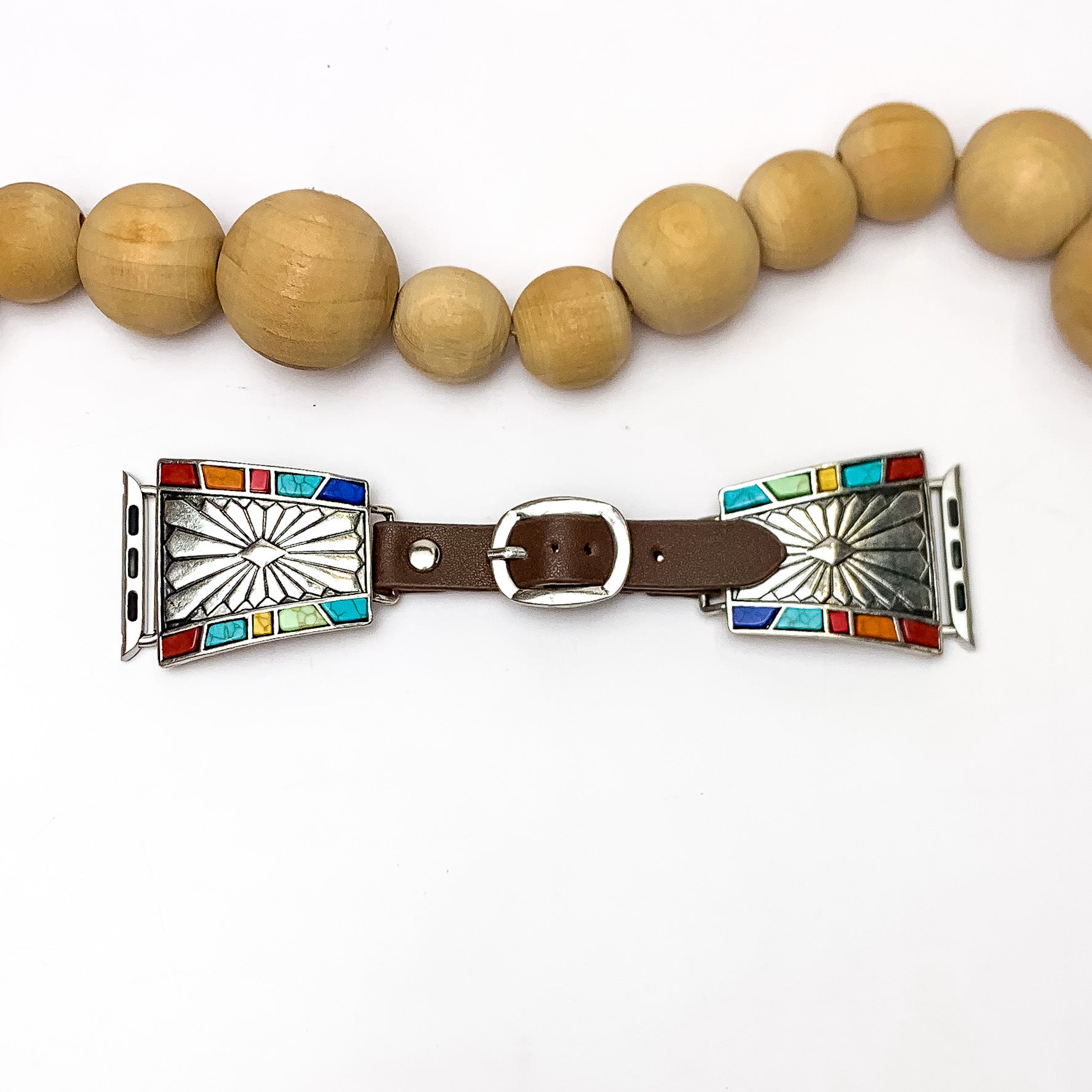 Brown Watch Band with Silver Tone Designs and Multicolor Stones. Pictured on a white background with wood beads above the watch band for decoration.