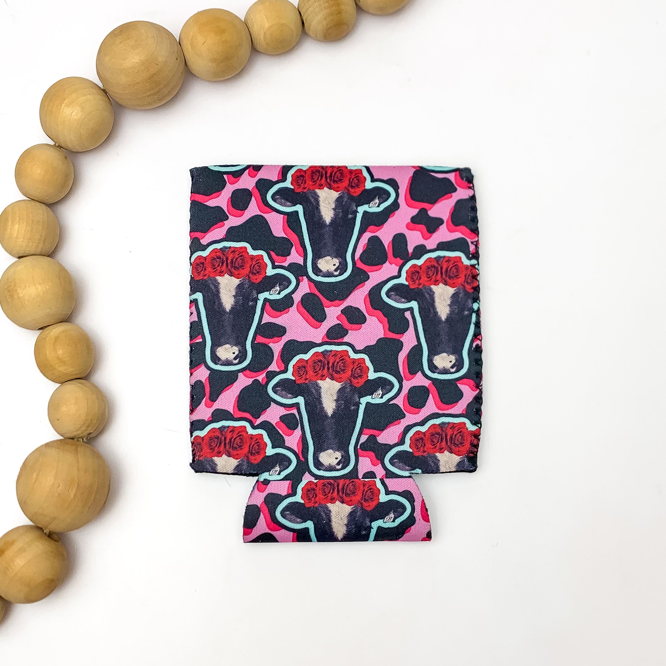 Cow Head Print with Pink and Black Cow Print Koozie. Pictured on a white background with wood beads to the left of the koozie.