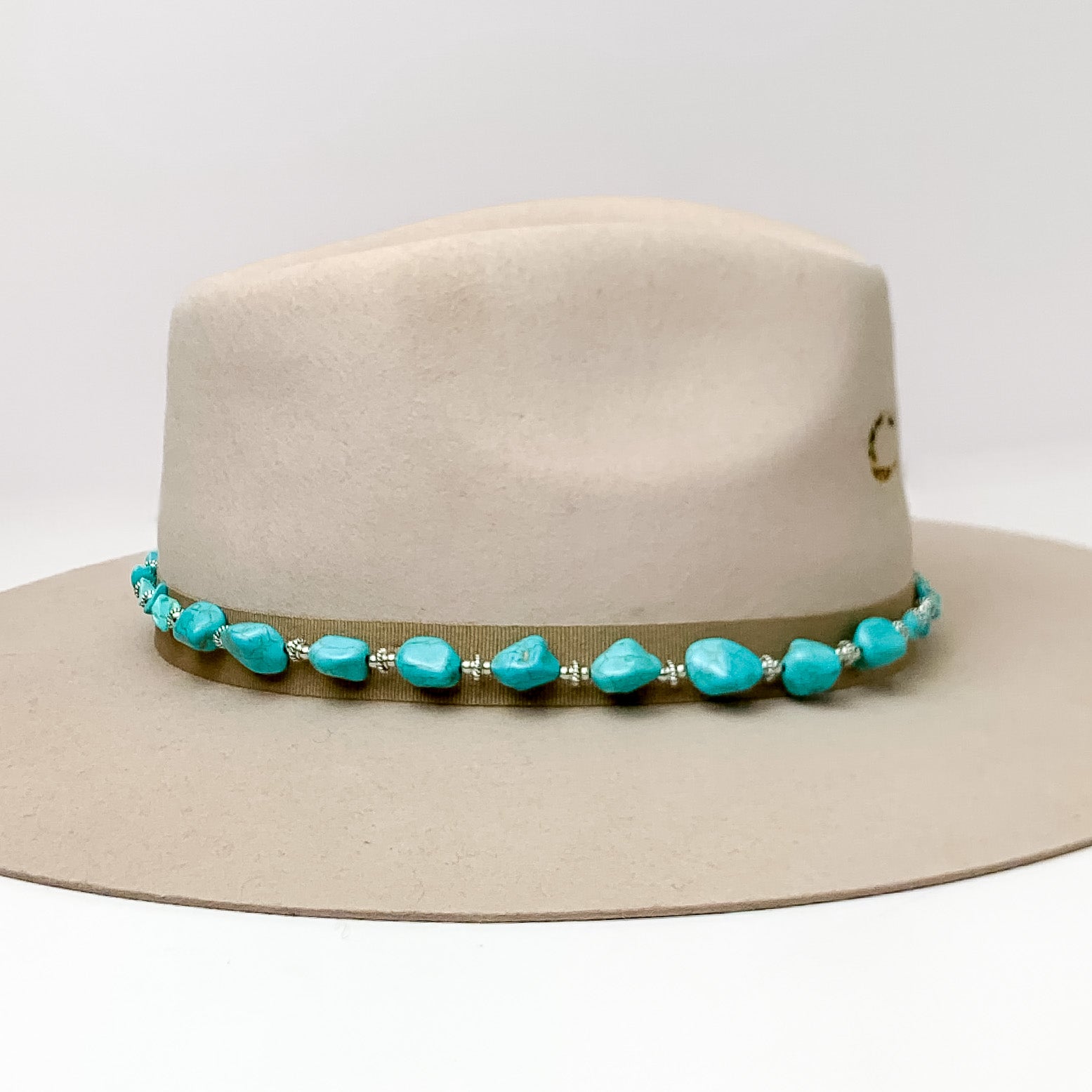 Hat Band With Large Turquoise Stones and Light Brown Ties. Pictured on a light brown hat with a white background.