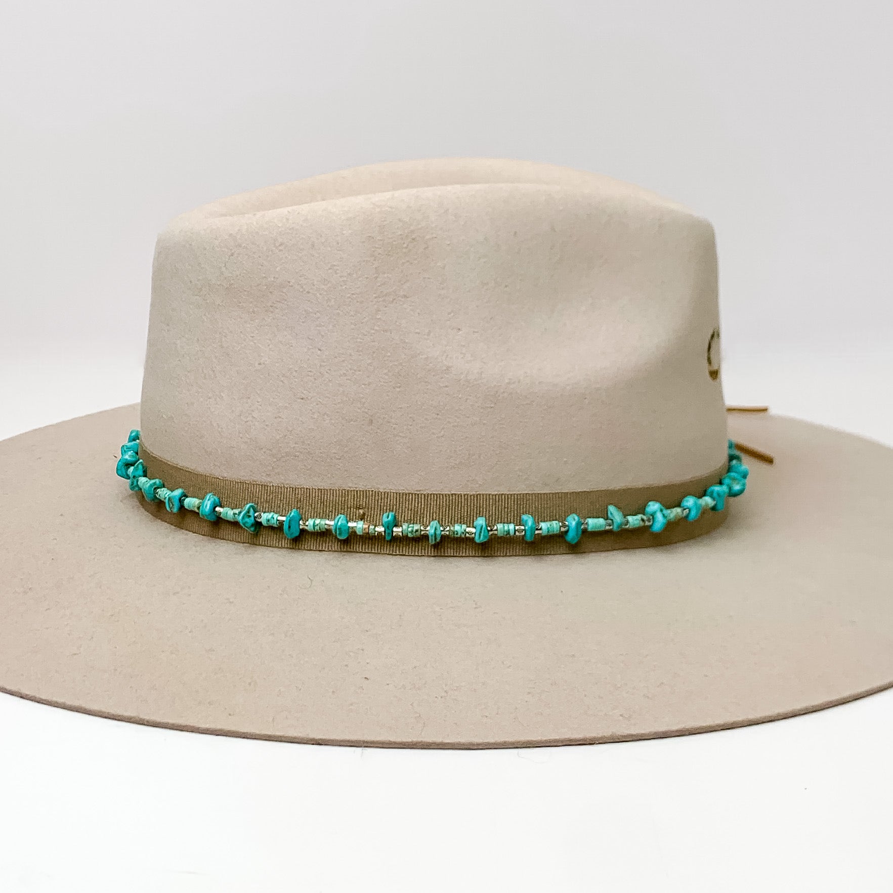 Hat Band With Turquoise Stones and Light Brown Ties. Pictured on a light brown hat with a white background.