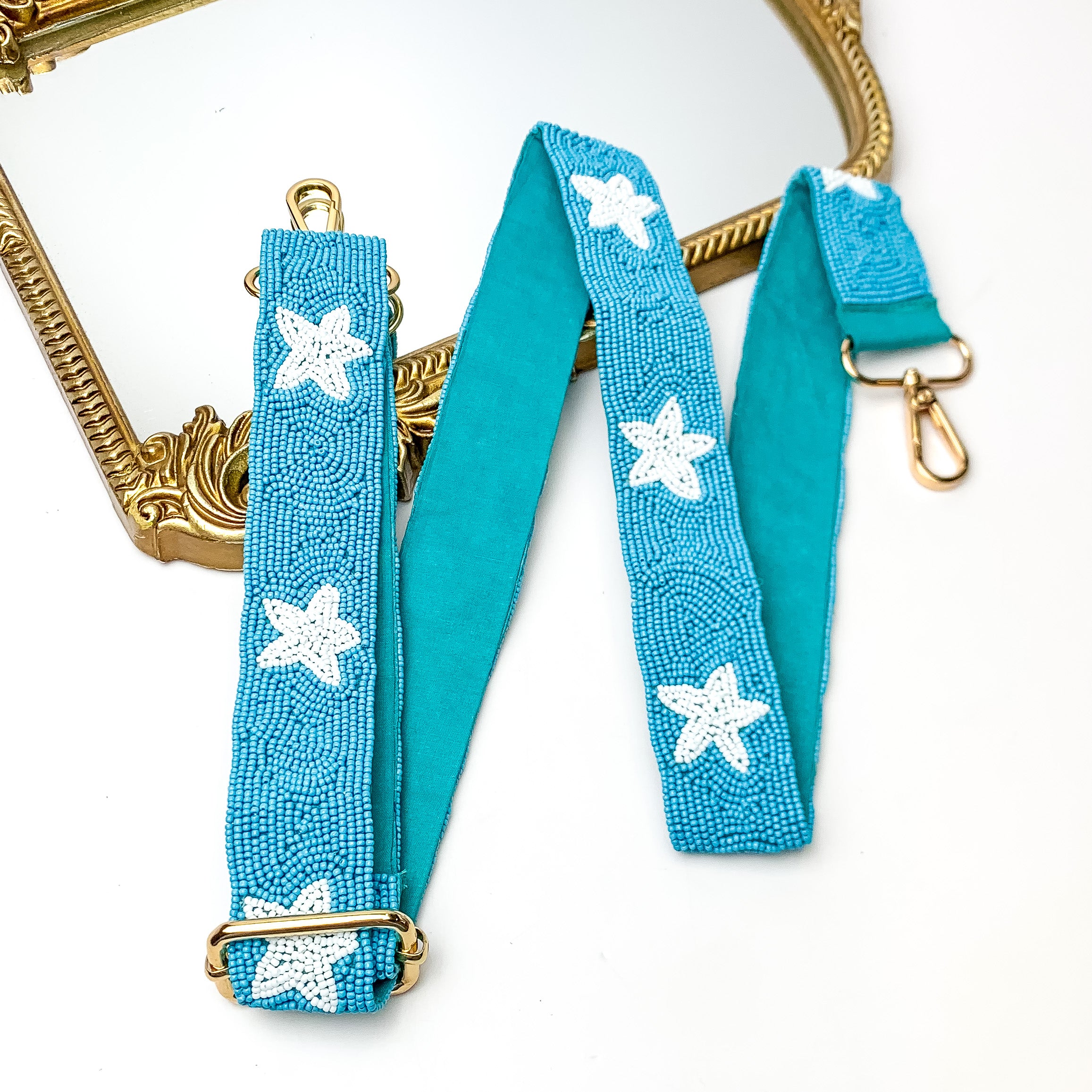 Star of the Show Beaded Adjustable Purse Strap in Blue and White. This purse strap is pictured on a white background with a gold trimmed mirror in the corner.