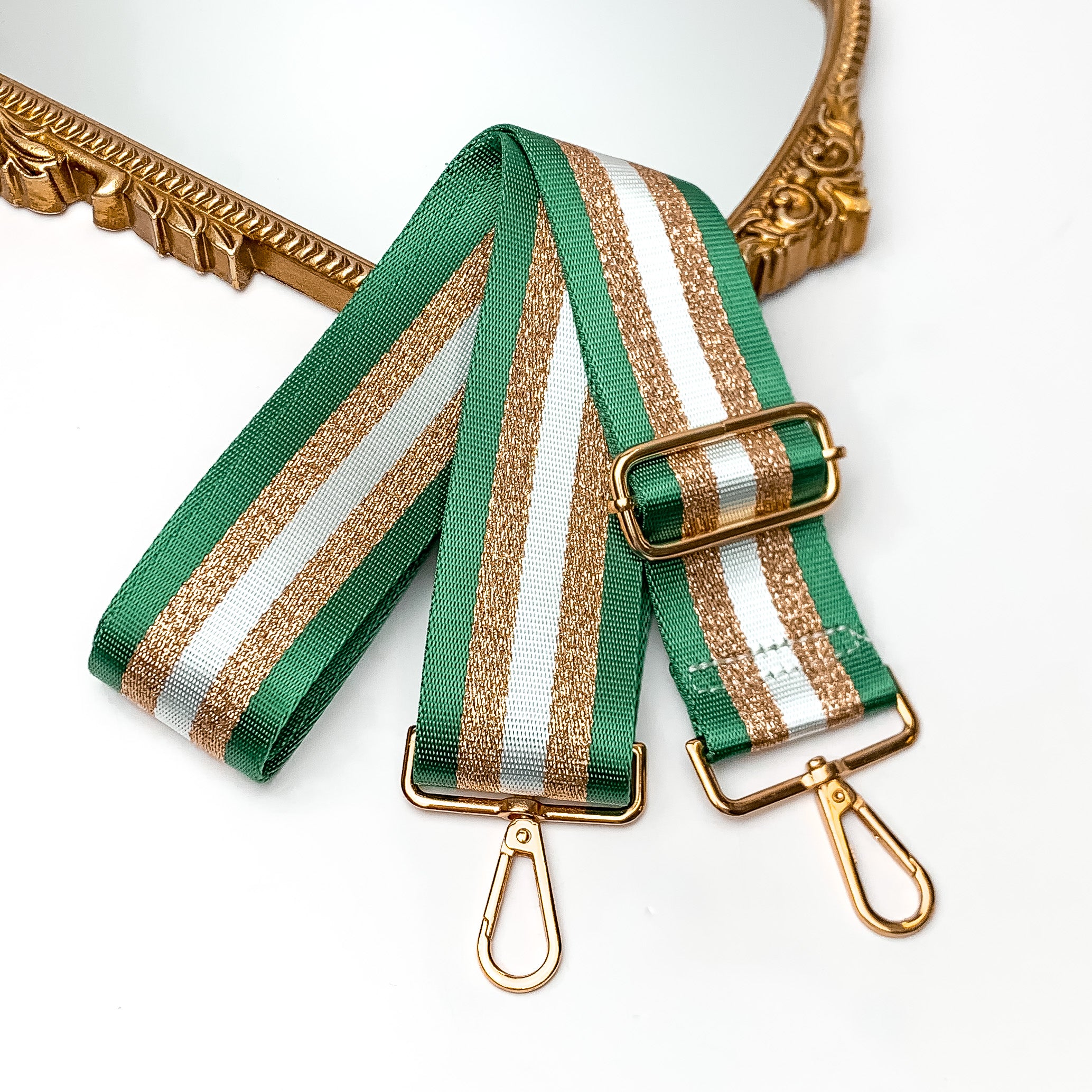 Striped Adjustable Purse Strap in Green. This purse strap is pictured on a white background with a gold trimmed mirror in the corner.