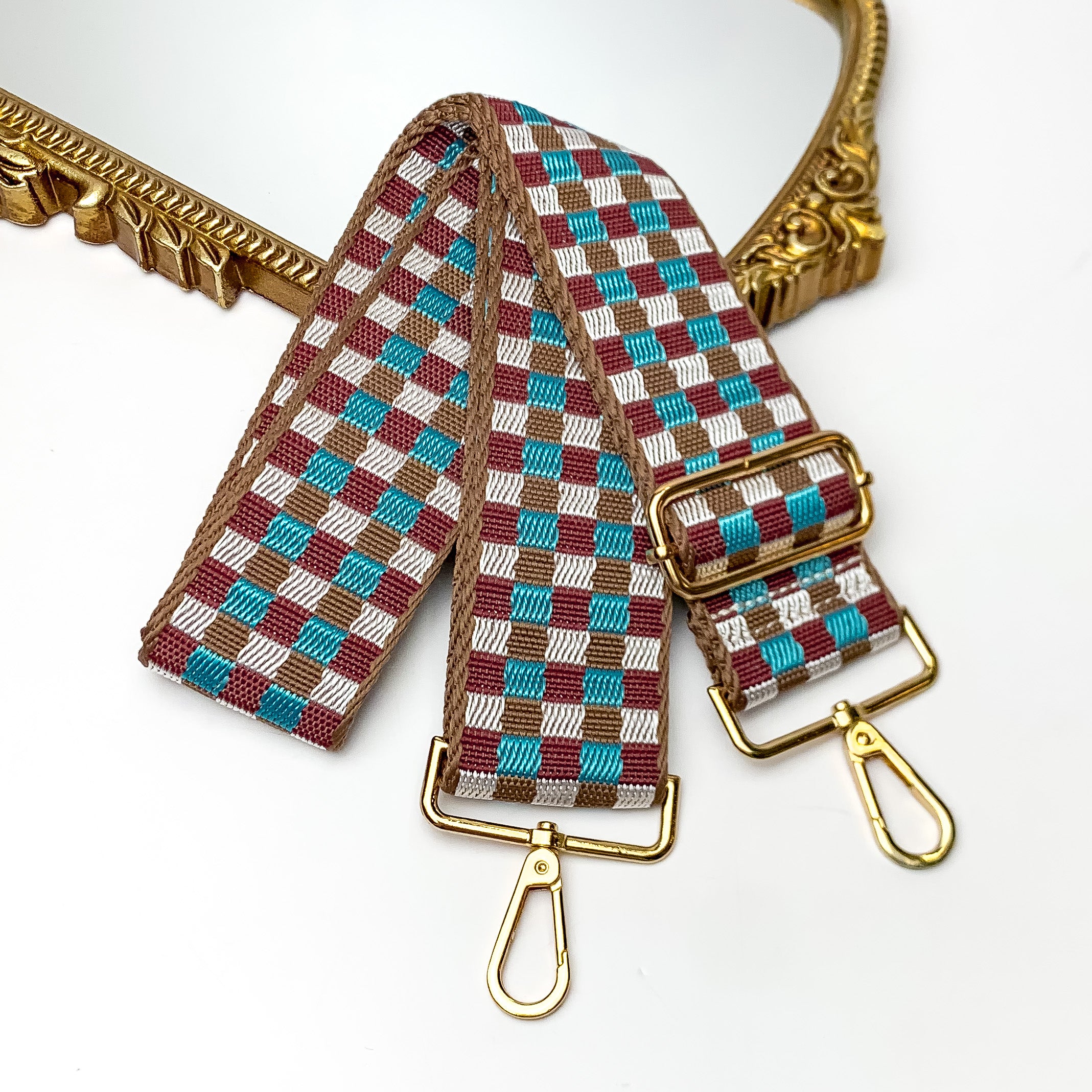 Checkered Adjustable Purse Strap in Brown and Blue. This purse strap is pictured on a white background with a gold trimmed mirror in the corner.
