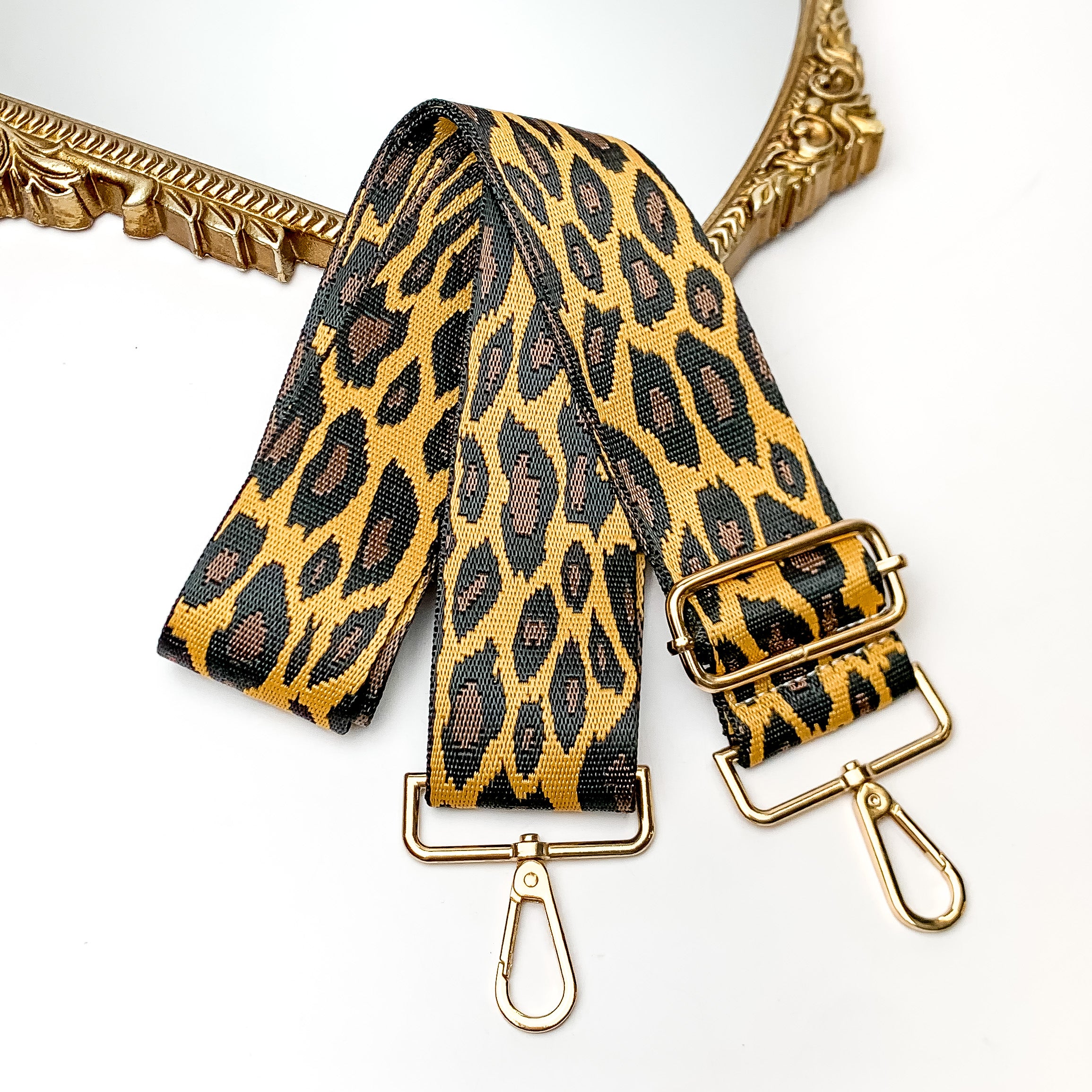 Cheetah Print Adjustable Purse Strap. This purse strap is pictured on a white background with a gold trimmed mirror in the corner.