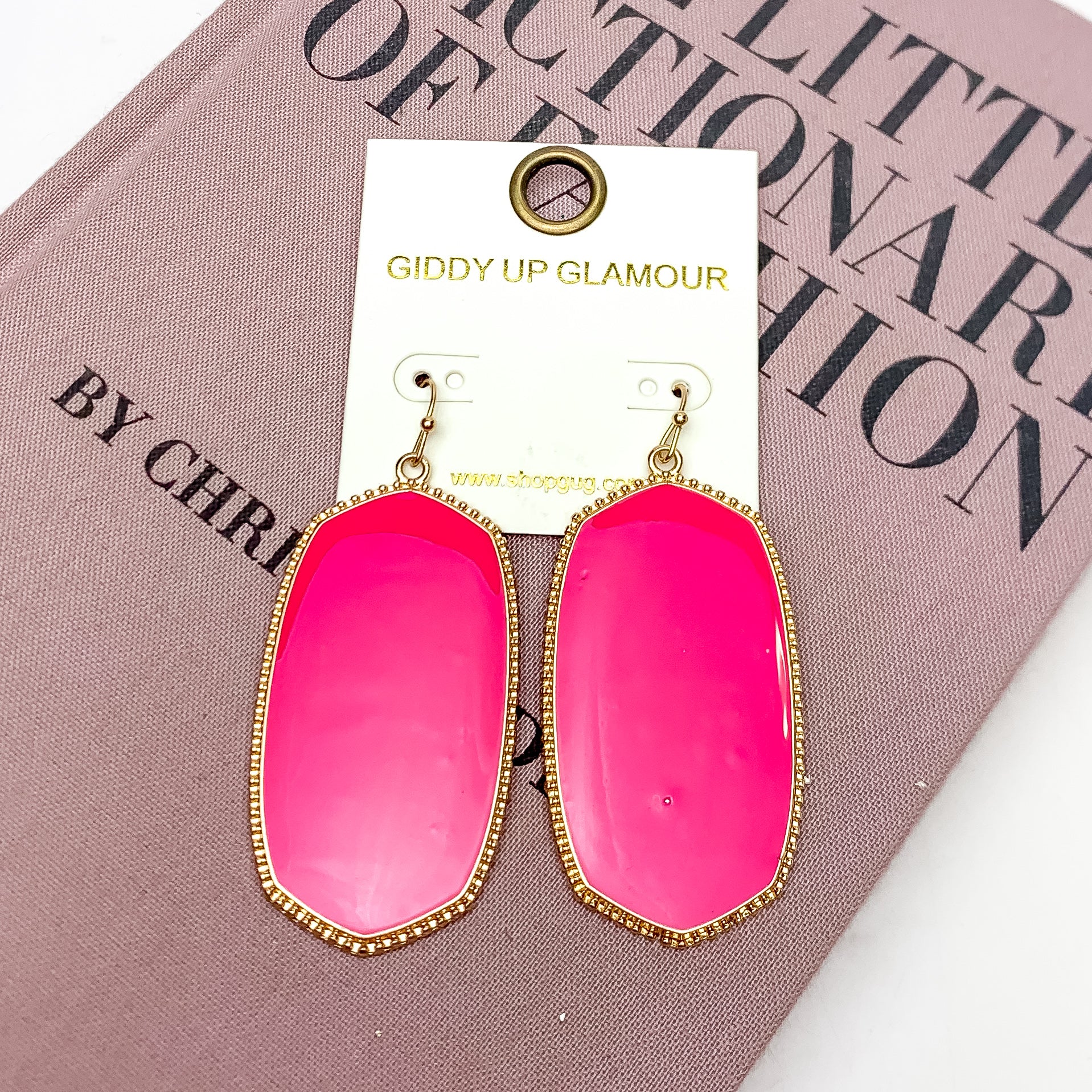 Southern Charm Oval Earrings in Hot Pink. These earrings are laying on a pink book with a white background behind the book.