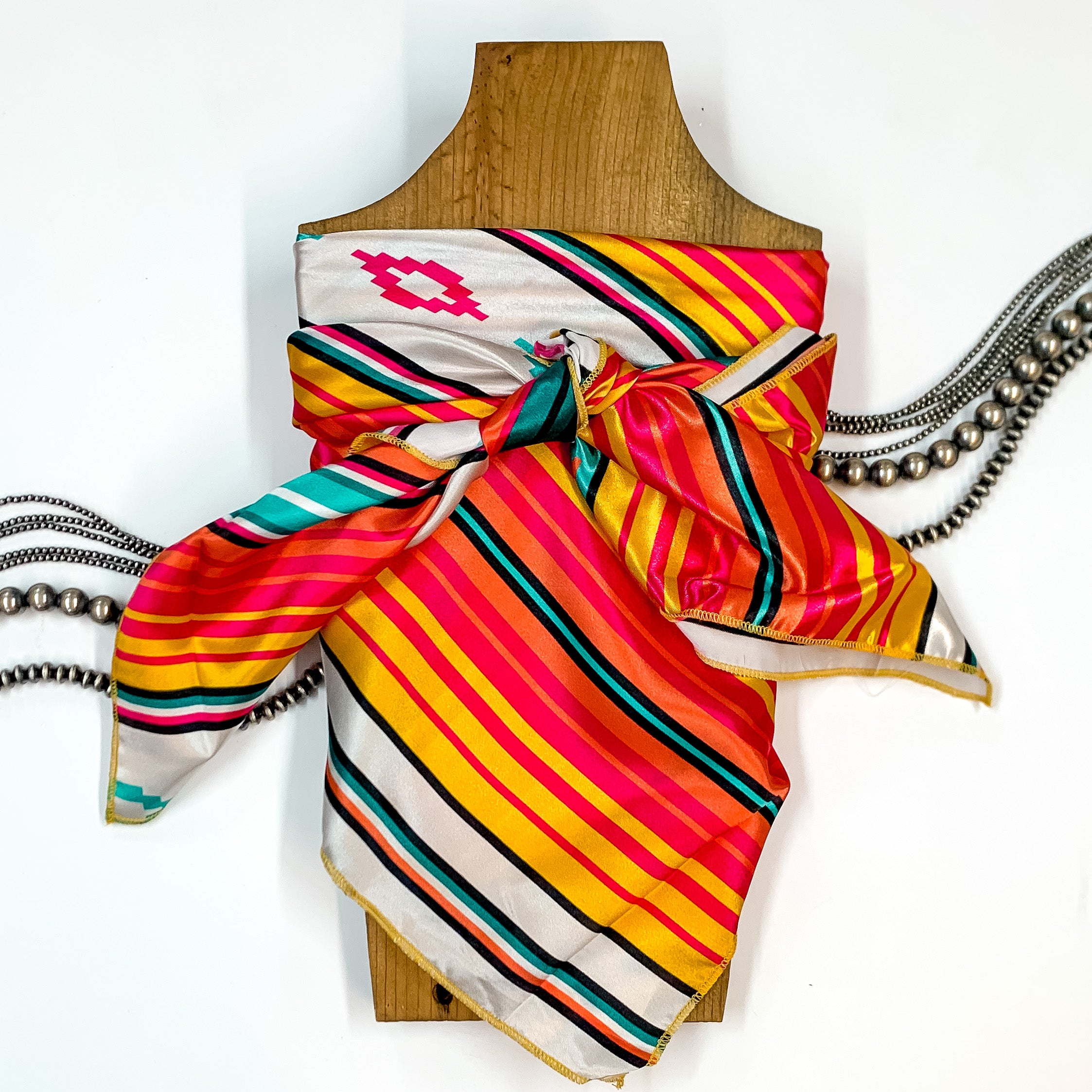 Solid colored scarf in Somerset Serape. Scarf is tied around a wooden piece. The scarf and piece of wood is pictured on a white background with Navajo jewelry spread out around it.