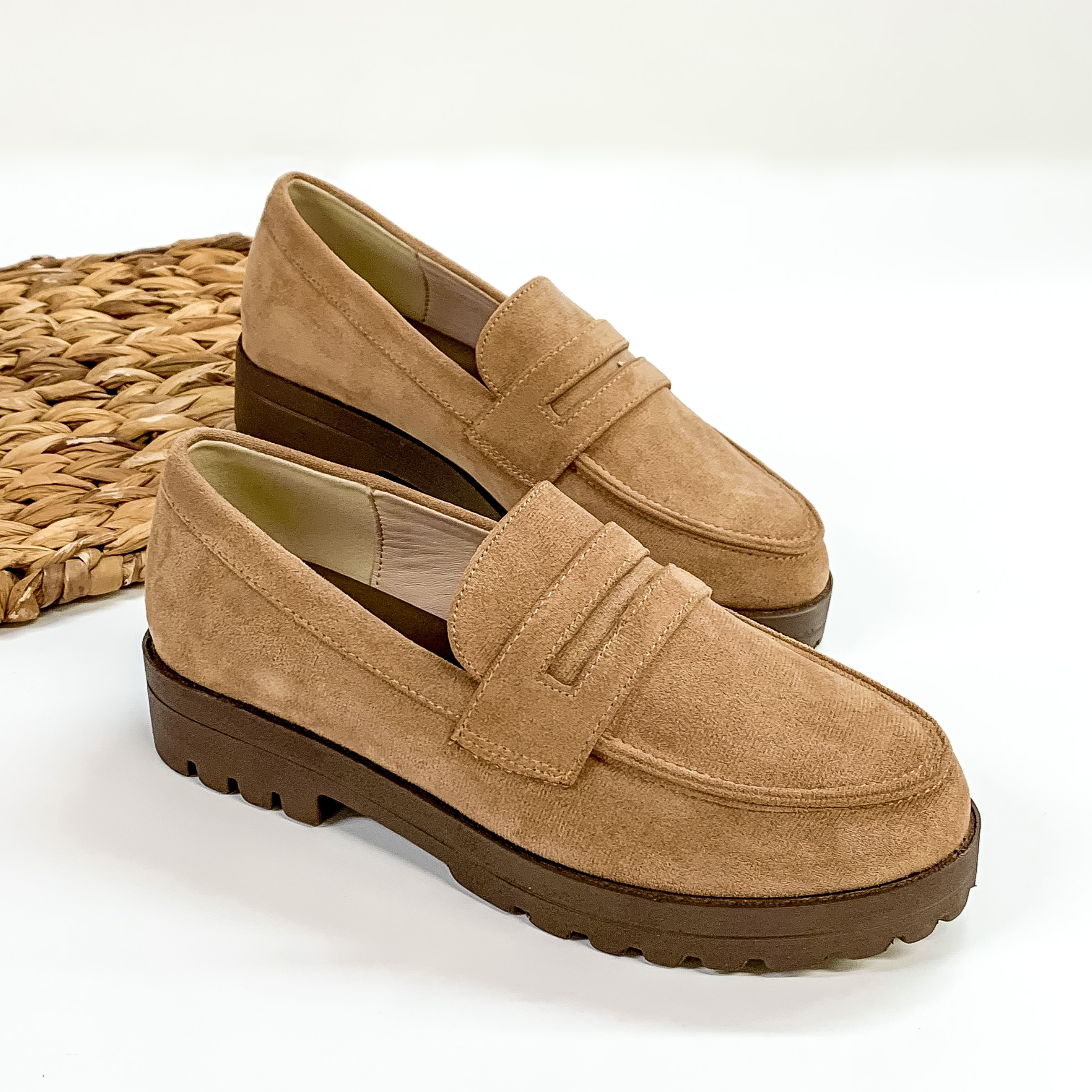Tan suede slip on loafers with a brown rubber sole. These loafers are pictured laying  on a white background. 