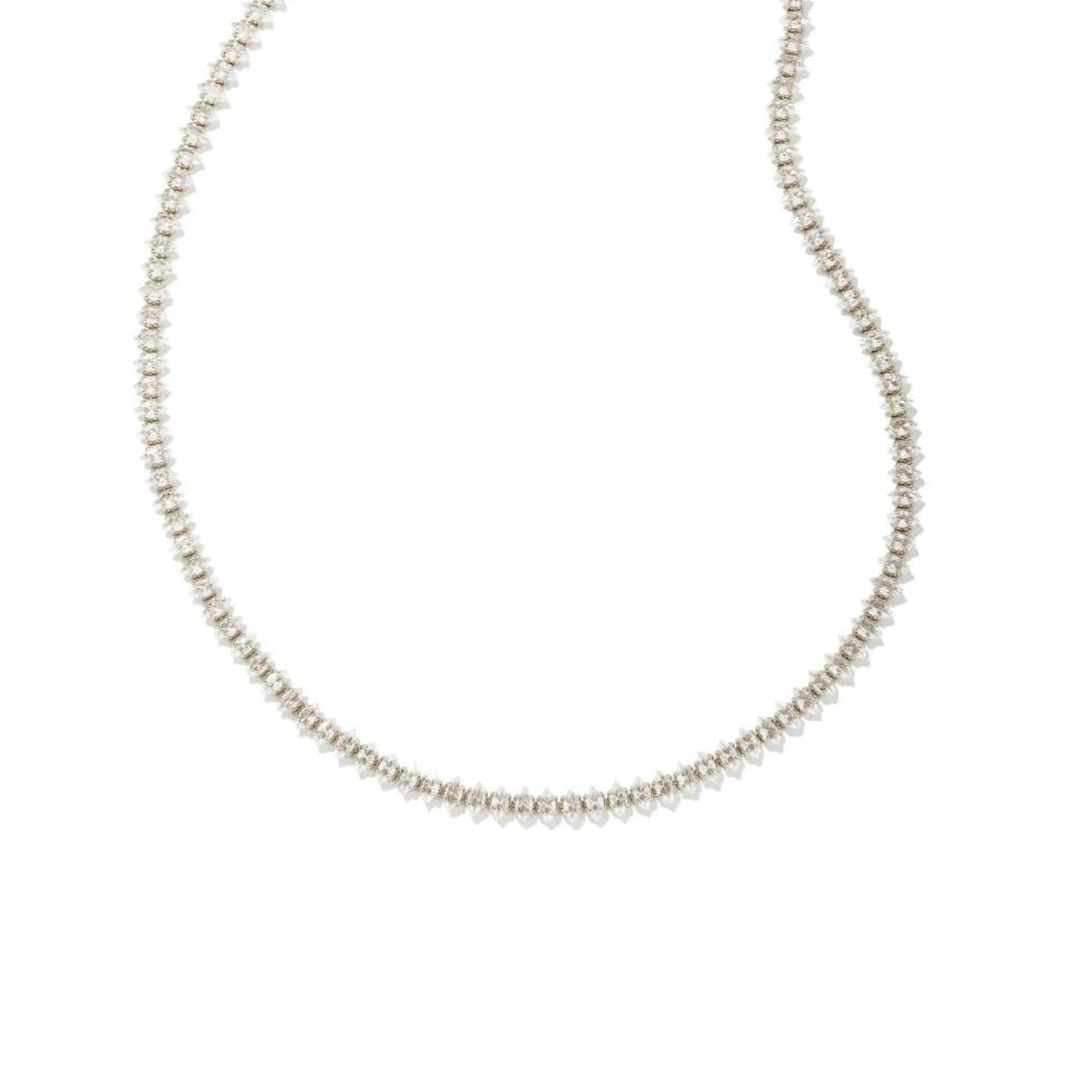 Pictured is a clear crystal tennis necklace in silver on a white background.