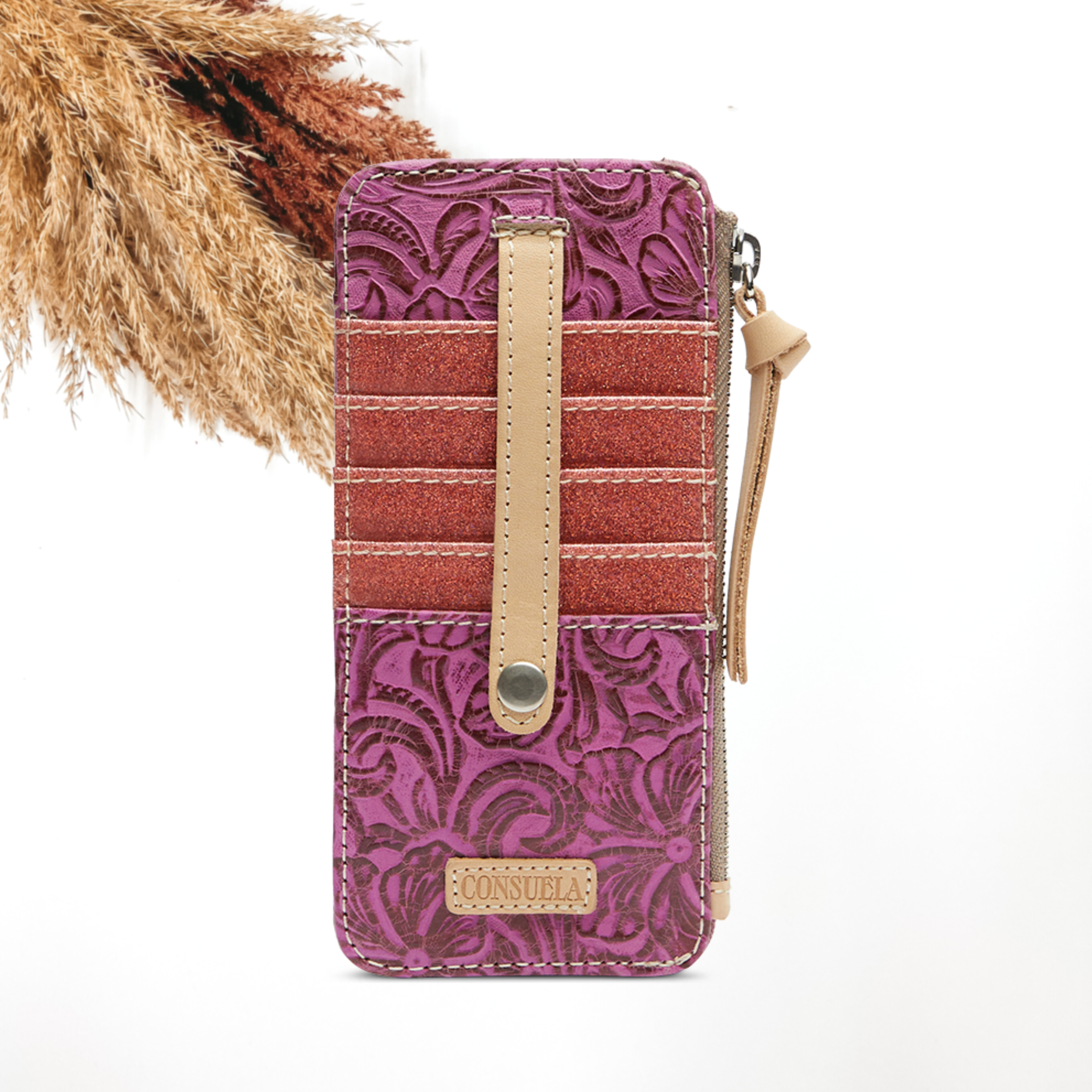 Pictured on a white background is a fuchsia, tooled leather print card organizer. This card organizer includes pink glittler pockets with a side zipper and tan leather tassel. 