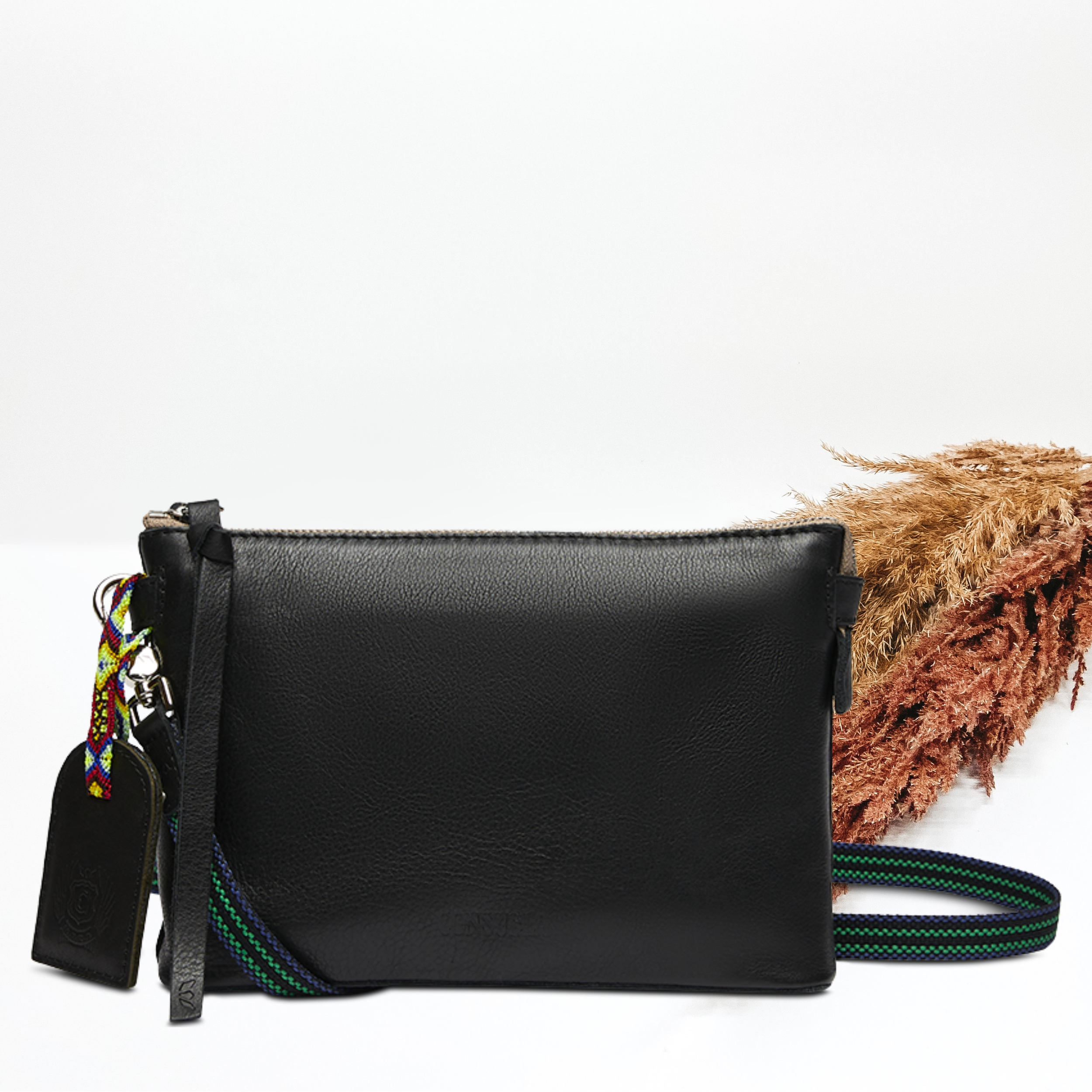 Pictured on a white background is black leather midtown crossbody purse. 