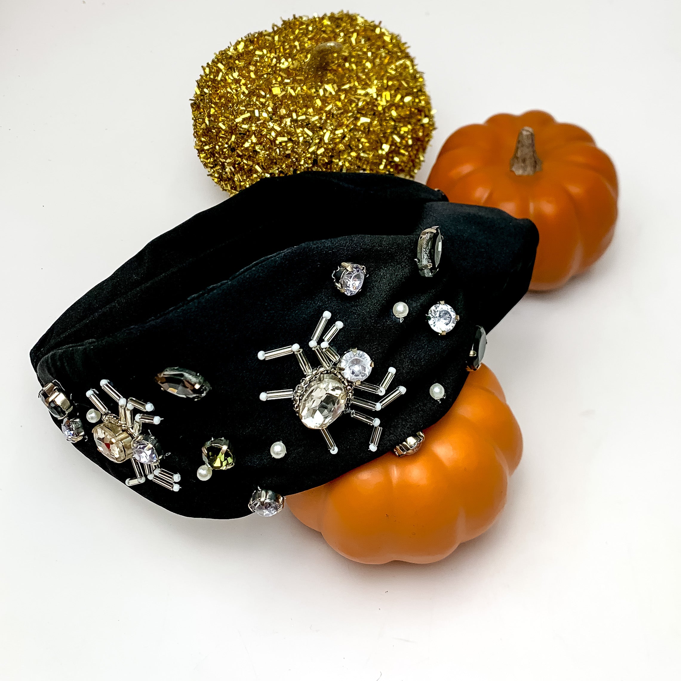 Halloween Clear Crystal Spider Headband in Black. This headband is pictured next to decorative pumpkins.