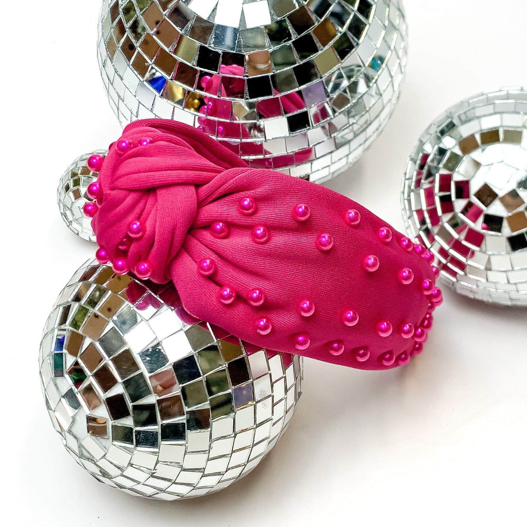 Hot Pink Headband With Pink Pearls. This headband is pictured on a white background and is surrounded by disco balls.