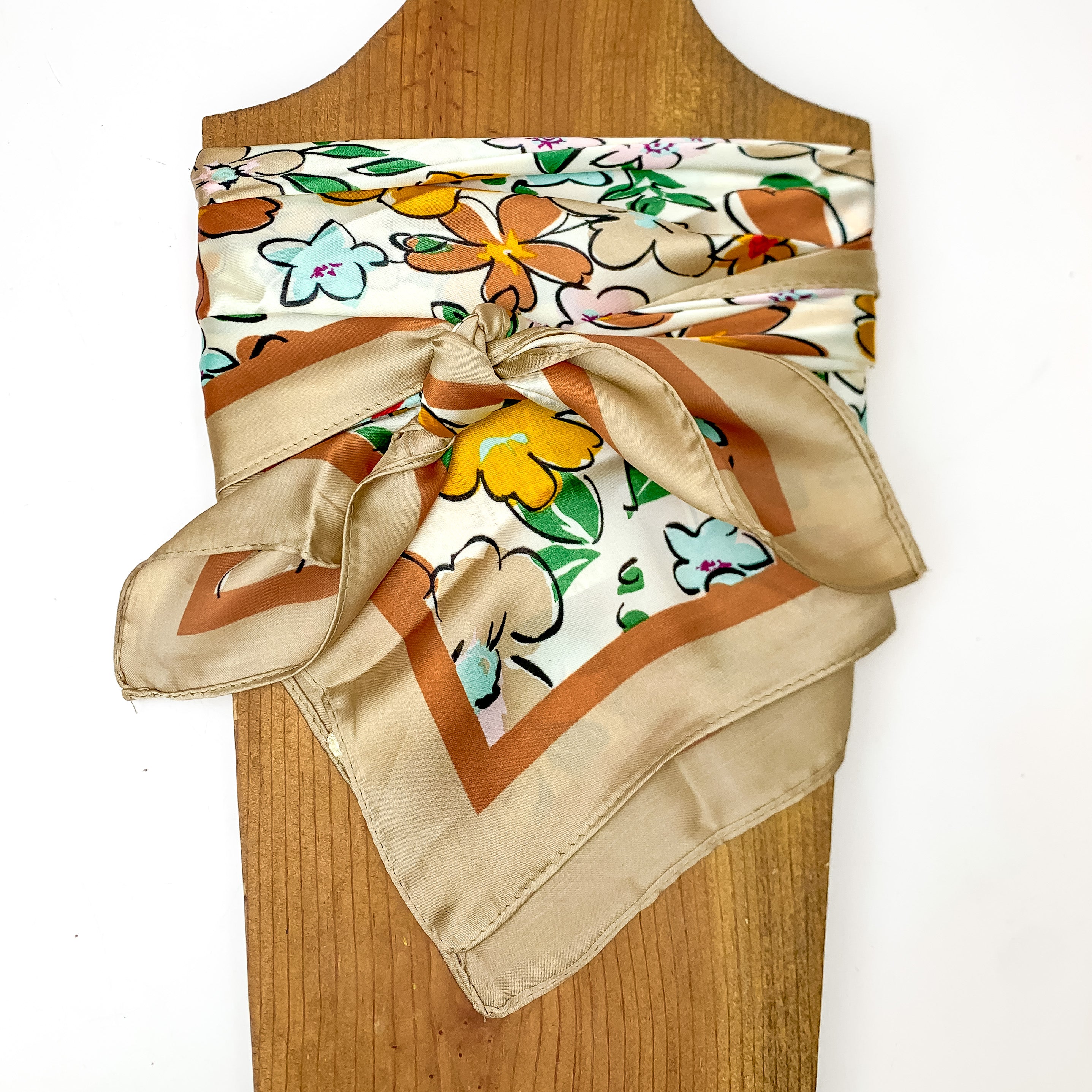 Flower Print Wild Rag in beige. This scarf is pictured tied around a wood piece with a white background.