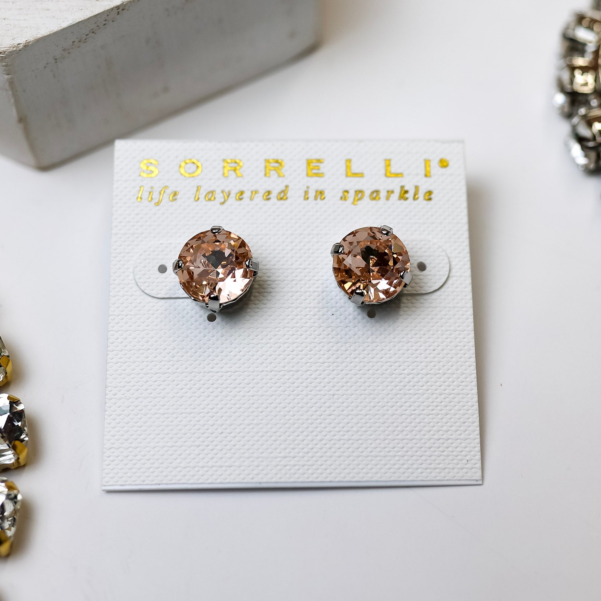 A pair of circle crystal stud earrings that are topaz. These earrings are pictured on a white background with crystal necklaces.