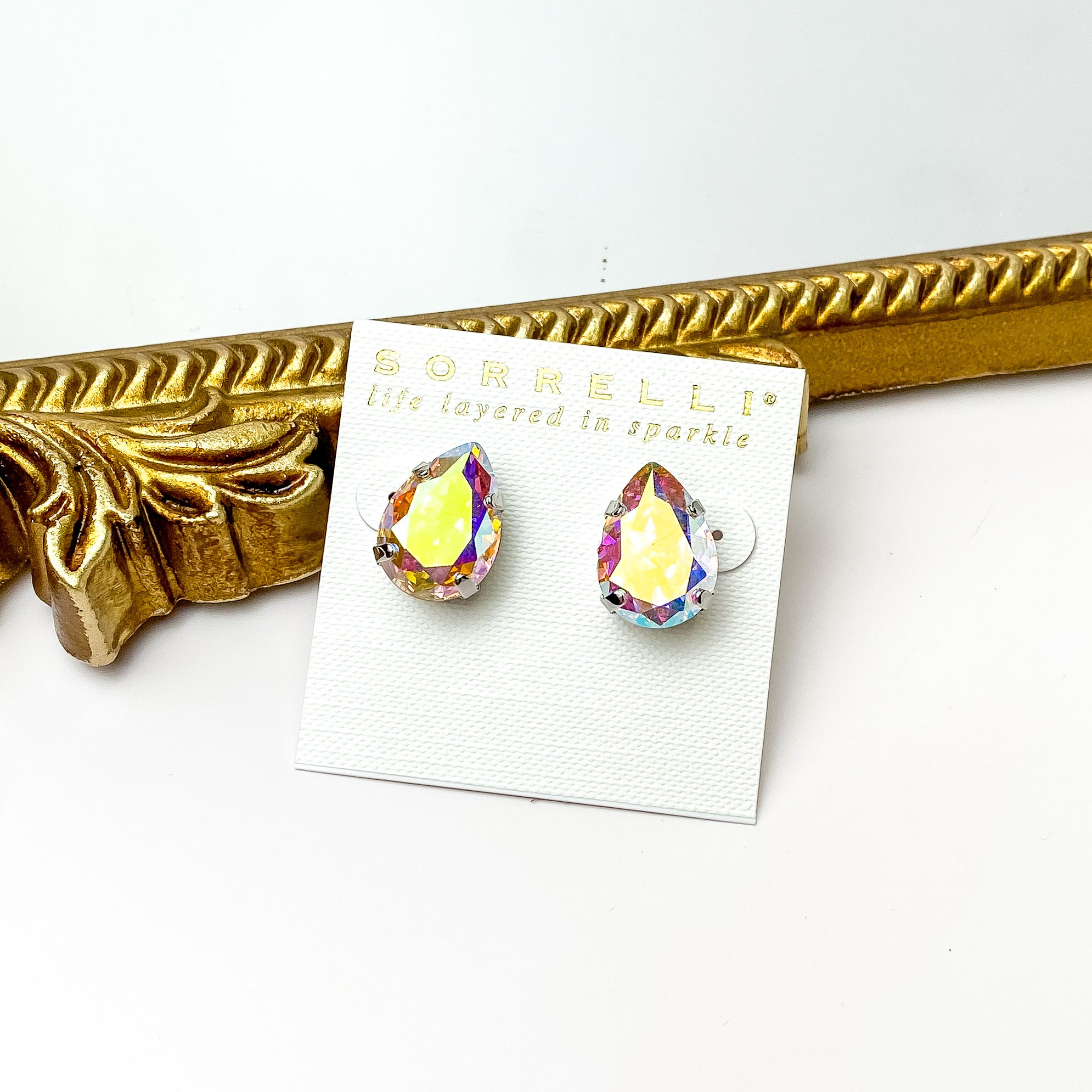 Single AB crystal stud earrings with a silver backing. Pictured on a white background with a gold figure through the middle