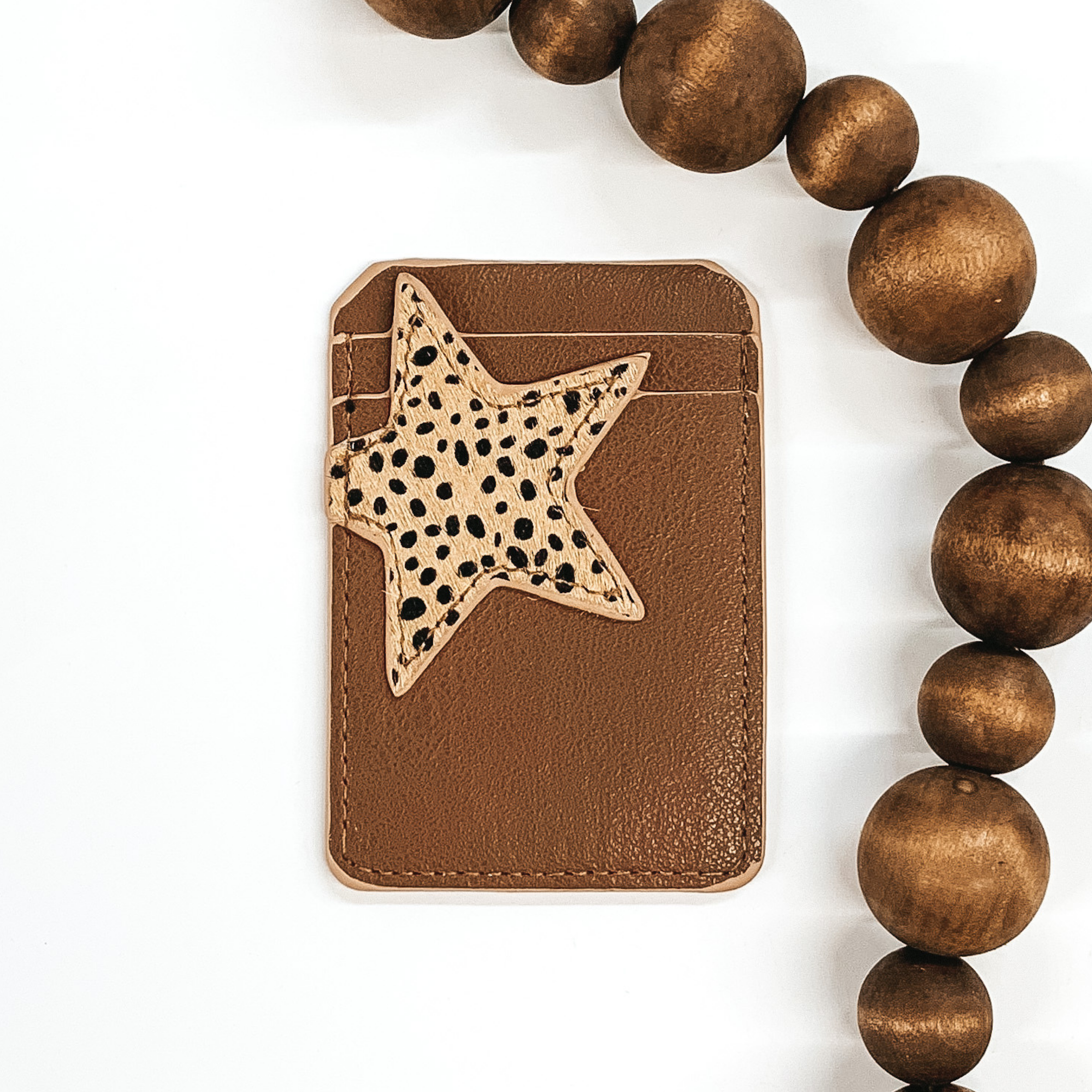 Brown card holder with two pockets that has a beige colored star with a dotted print on the front and can stick to the back of phones/phone cases