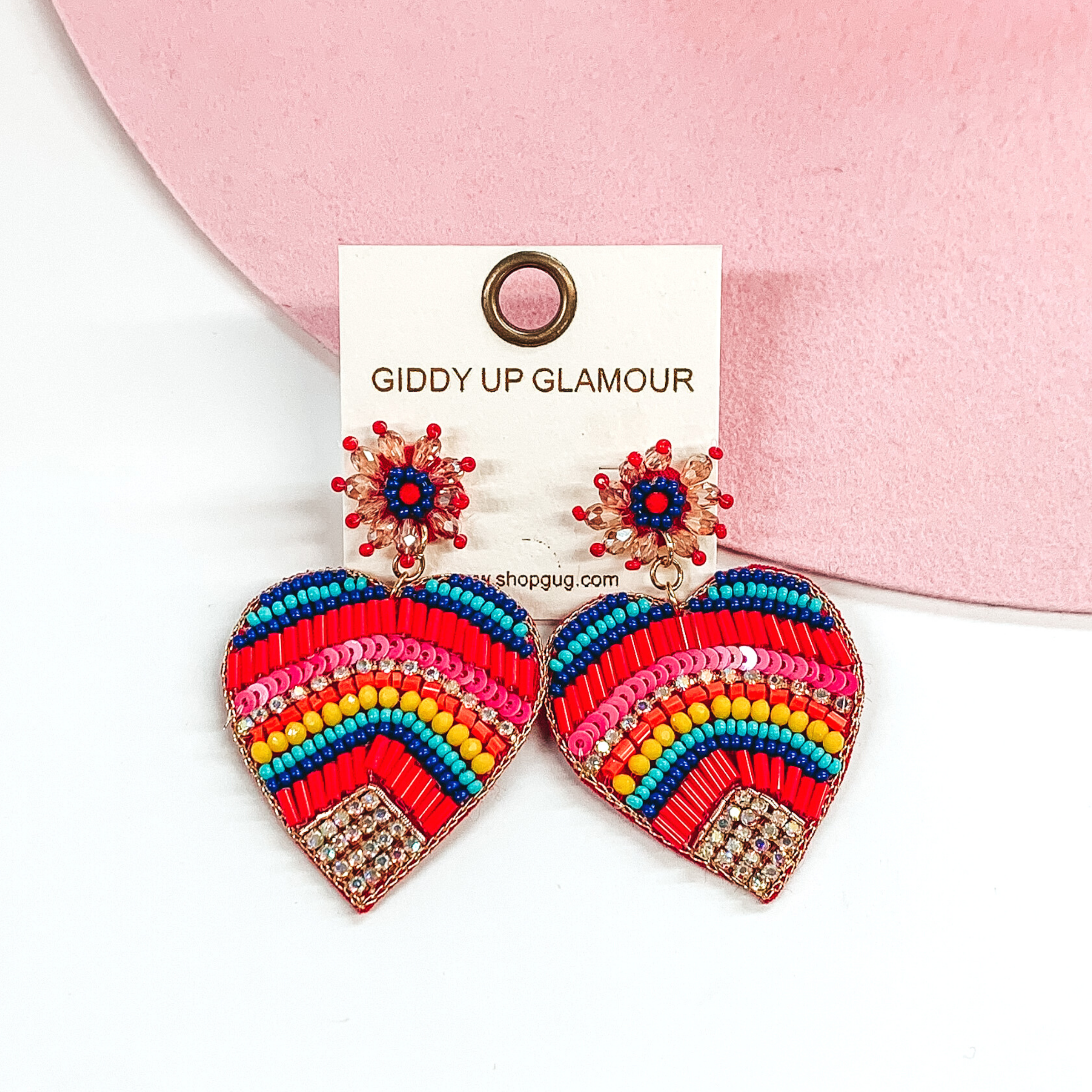 Beaded heart earrings that has multiple earrings. These earrings are pictured on a white and pink background. 