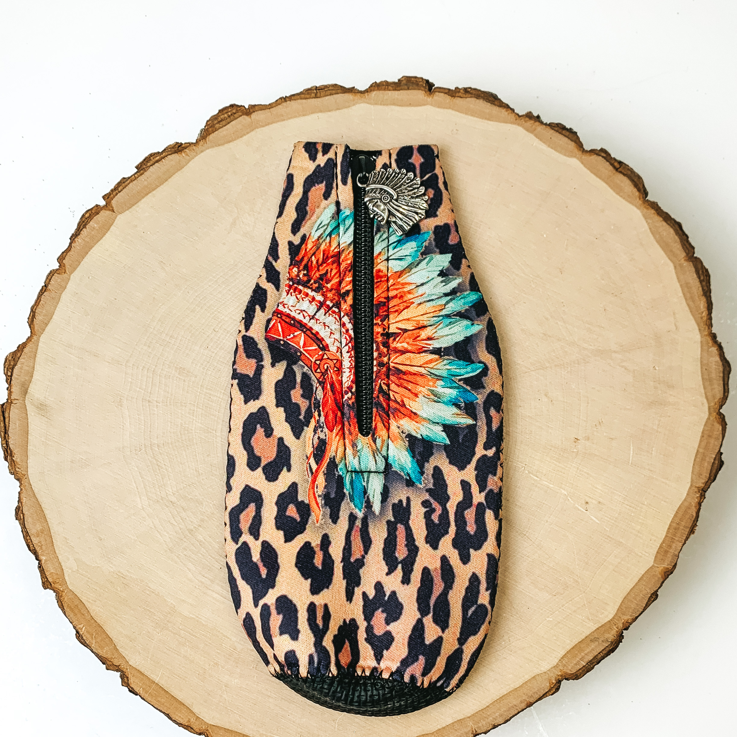 This Native American and Leopard Print Zip Up Koozie with Native American Charm is pictured on a peice of wood, with a white background. 