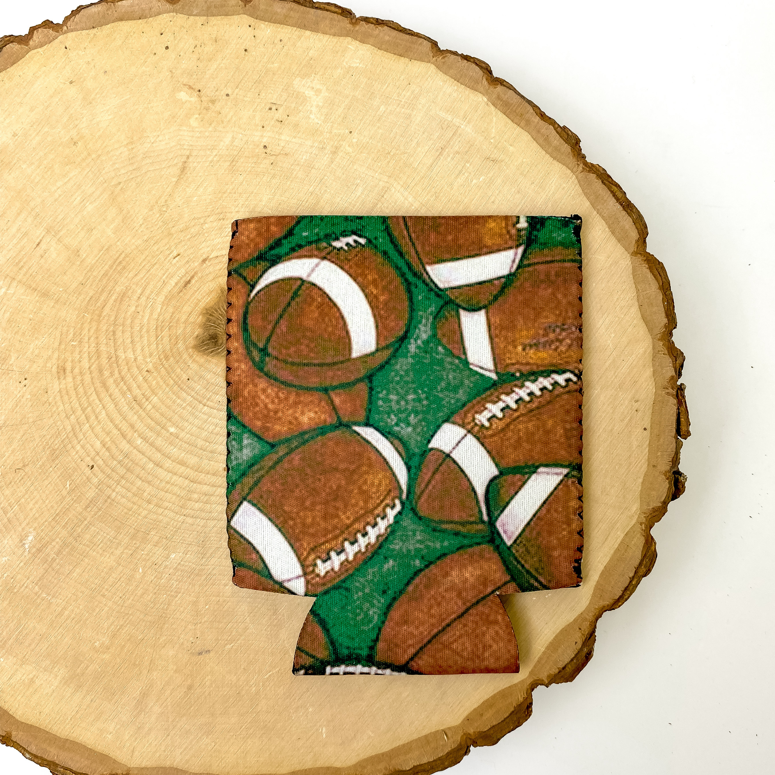Football Print koozie with a faded green background. This koozie is pictured on a piece of wood on a white background.