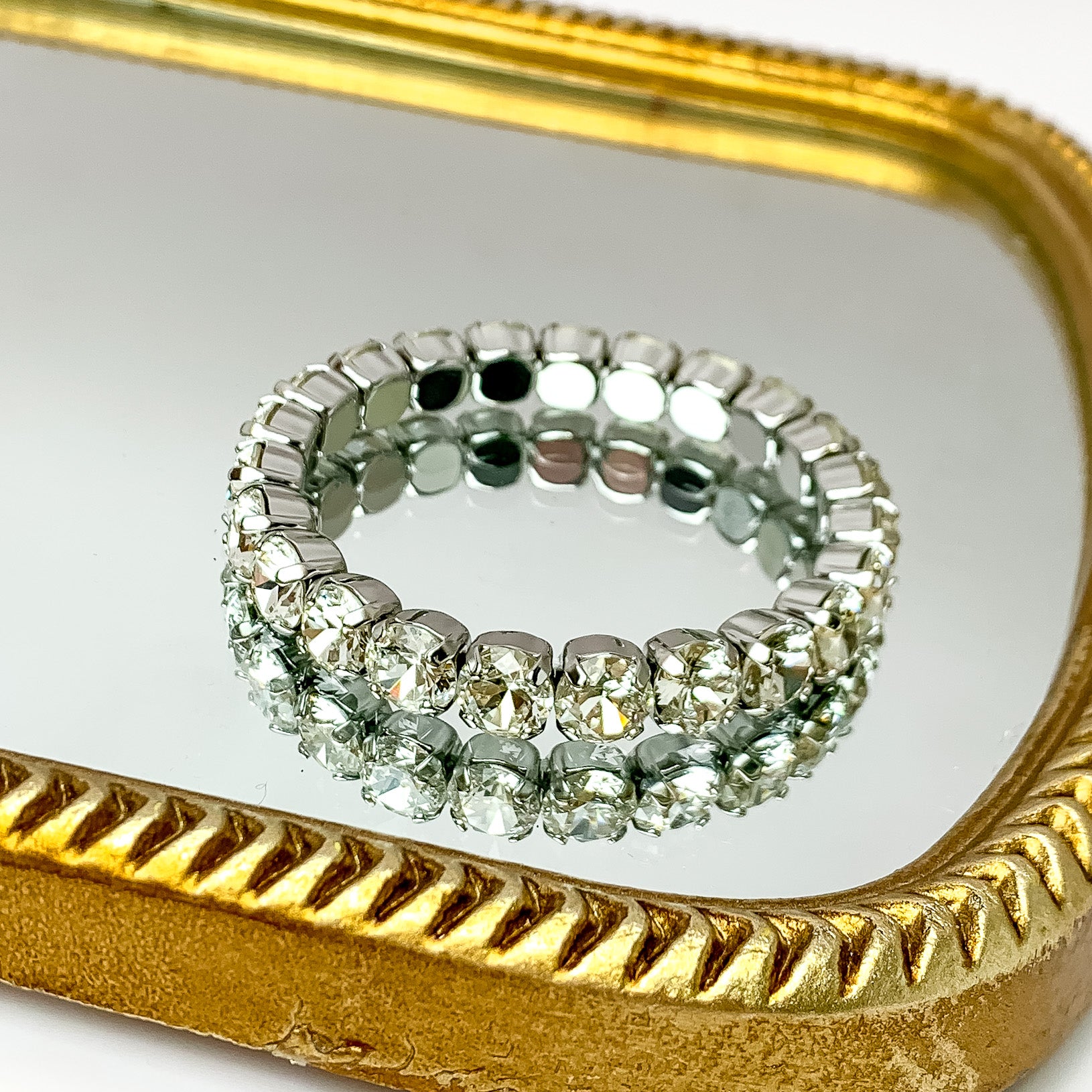 Single crystal layered bracelet stretchy to fit most wrists with silver undertones. Pictured on a mirror with a gold frame