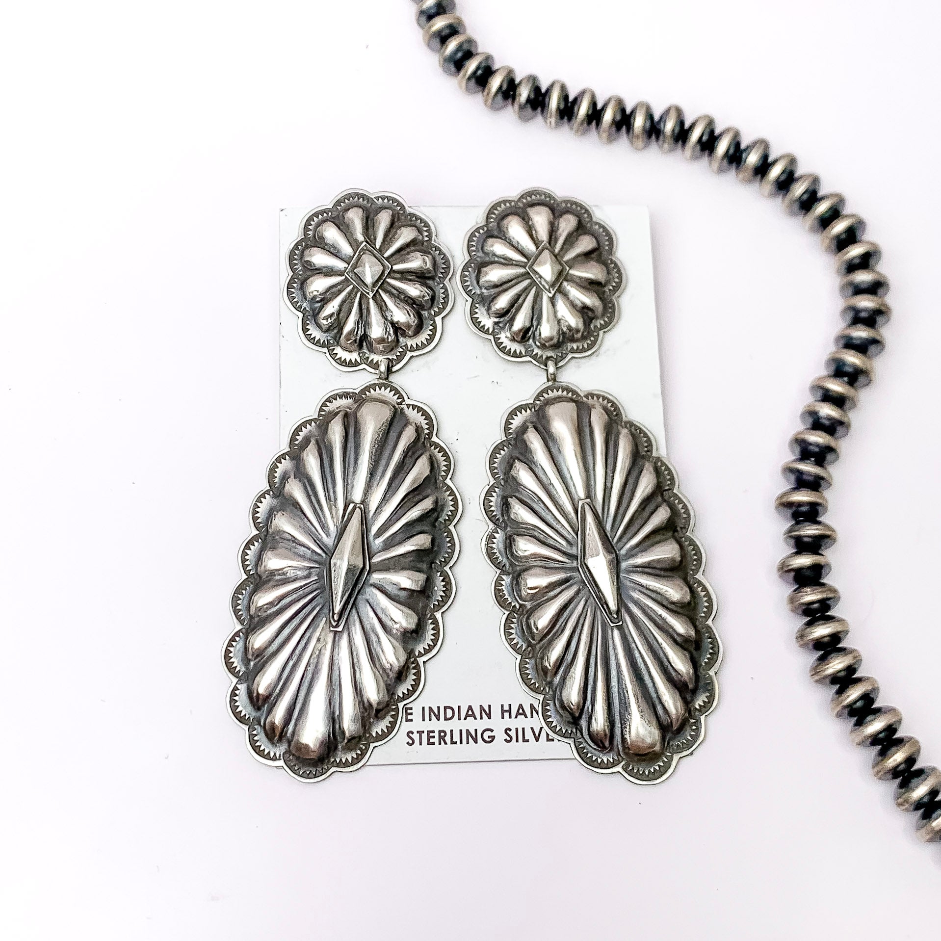 Centered in the picture is a pair of studded concho earrings on a white background. 