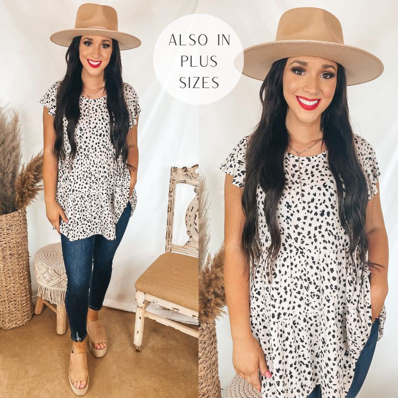 Models is wearing a tiered babydoll top that has a black leopard print on a white background. Model has it paired with dark wash skinny jeans, tan wedges, and a tan hat.