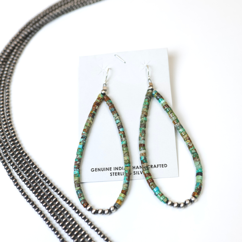 Navajo Handmade Turquoise Beaded Teardrop Earrings with Navajo Pearls are centered in the  picture, with navajo pearls laid to the left of the earrings. All is on a white background. 