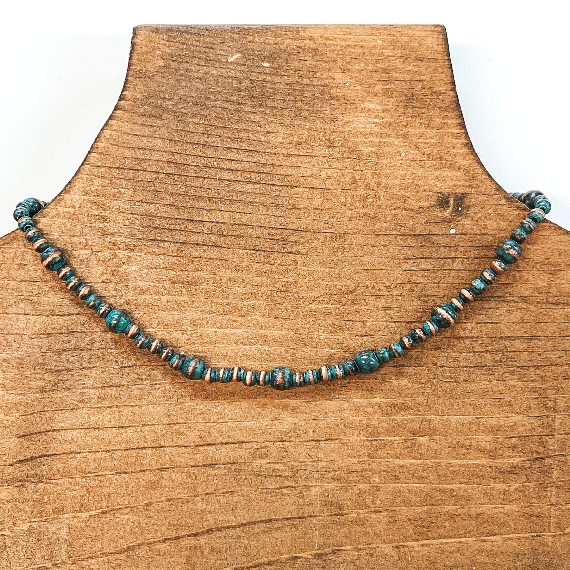 Patina beaded necklace with spacers in a larger size. This necklace is pictured on a brown necklace holder on a white background.