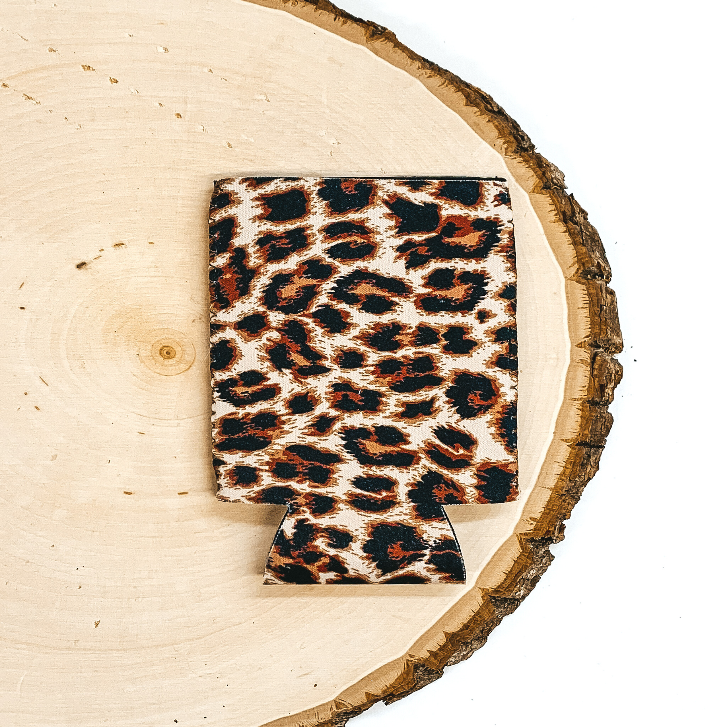 Leopard print koozie pictured laying on a piece of wood on a white background. 