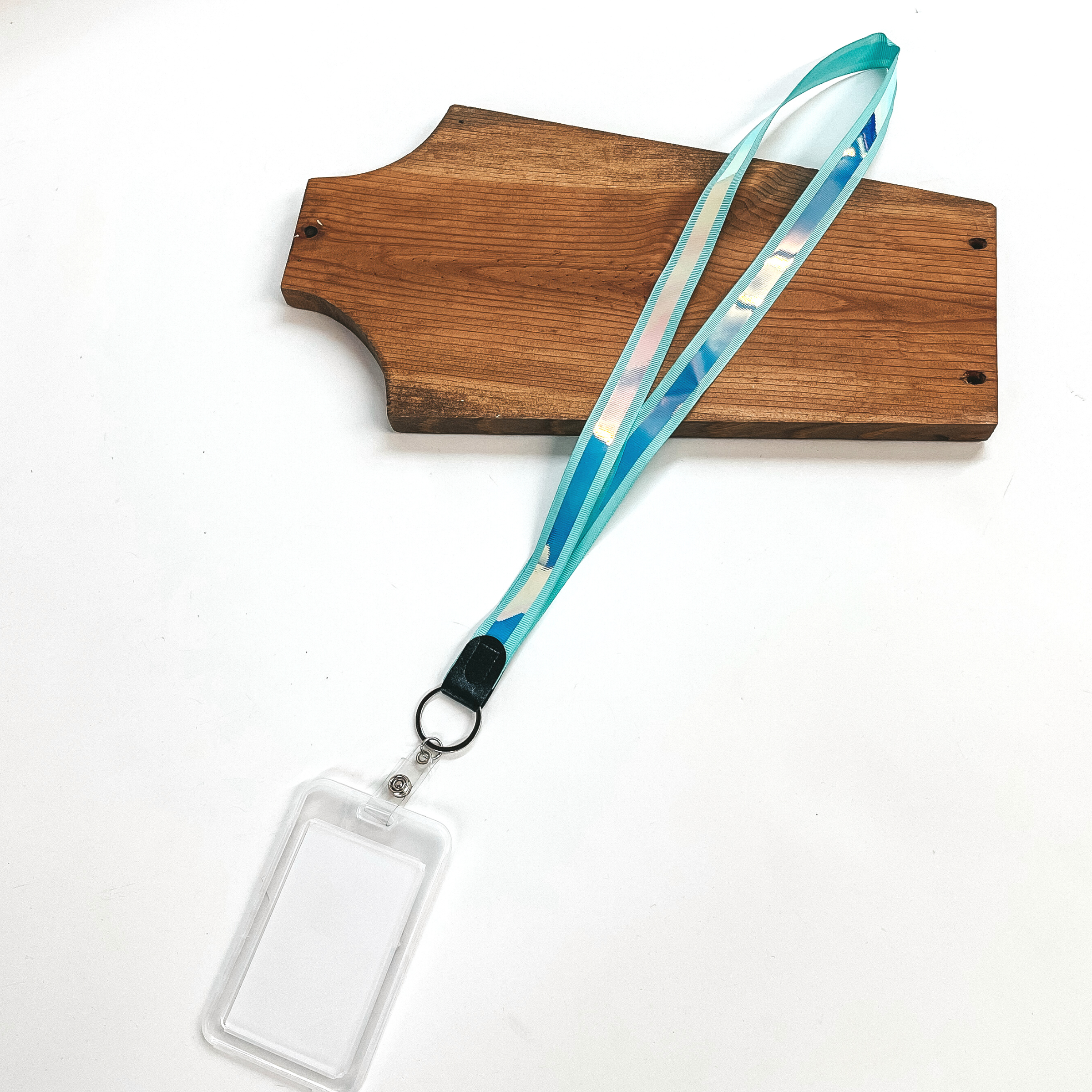 Mint ribbon lanyard with holographic center and clear ID holder, this  lanyard is laying on a brown necklace holder and on a white background.