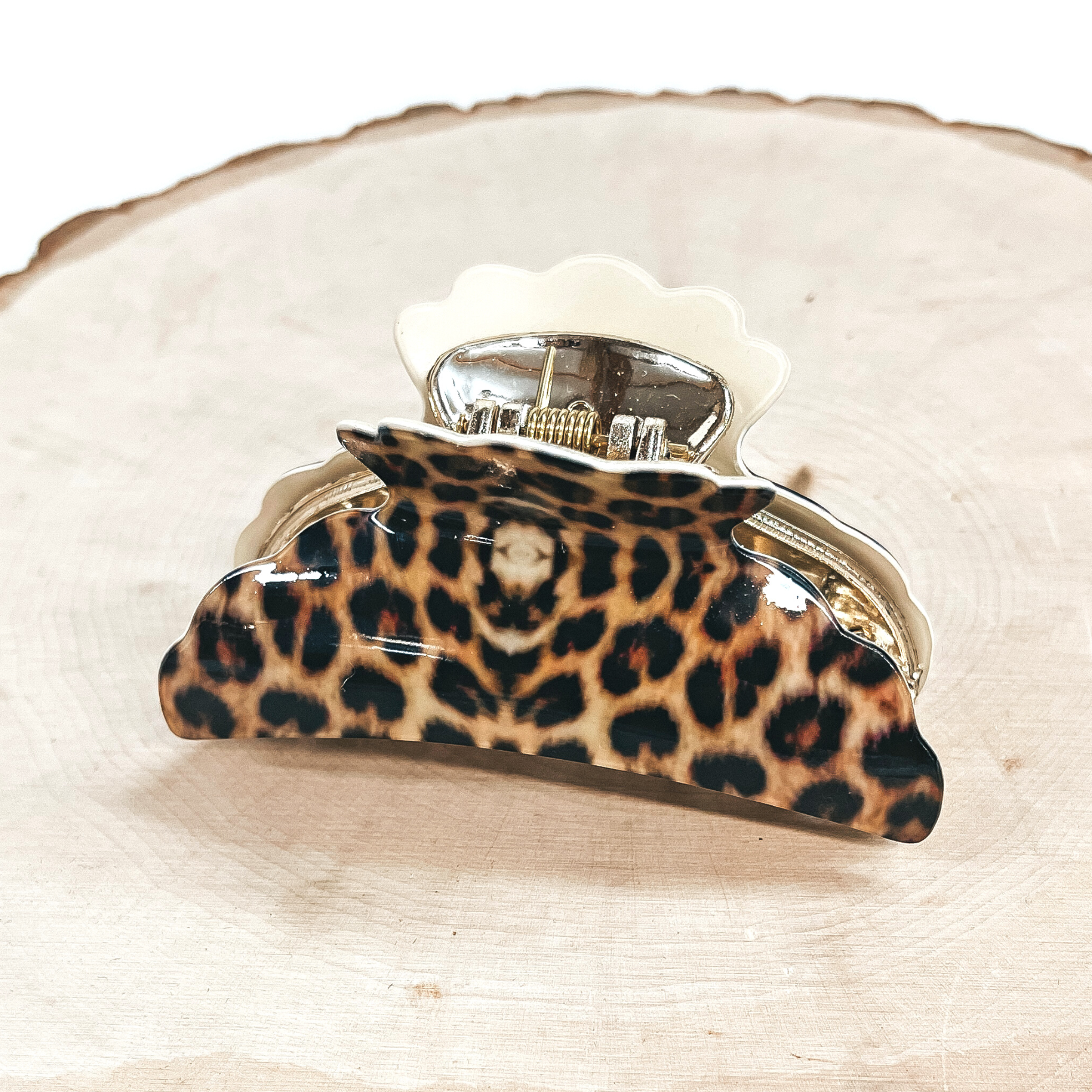 This is a yellow leopard print hair clip with a gold tone inlay in ivory.   This hair clip is taken on a slab of wood and on a white background.