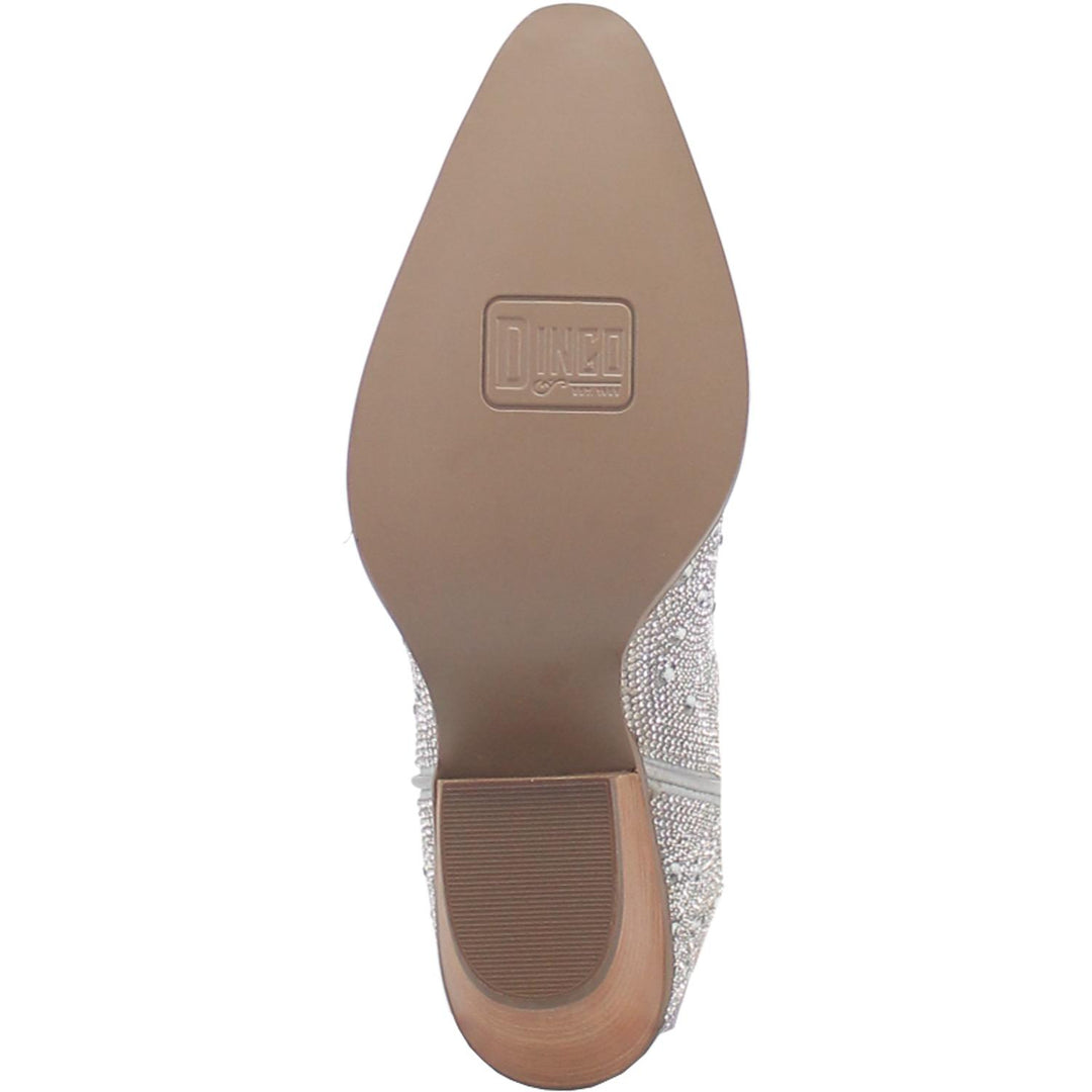 A mid calf length white boot with rhinestones from top to bottom, matching leather straps, a short heel, and a V cut at the top. Item is pictured on a white background