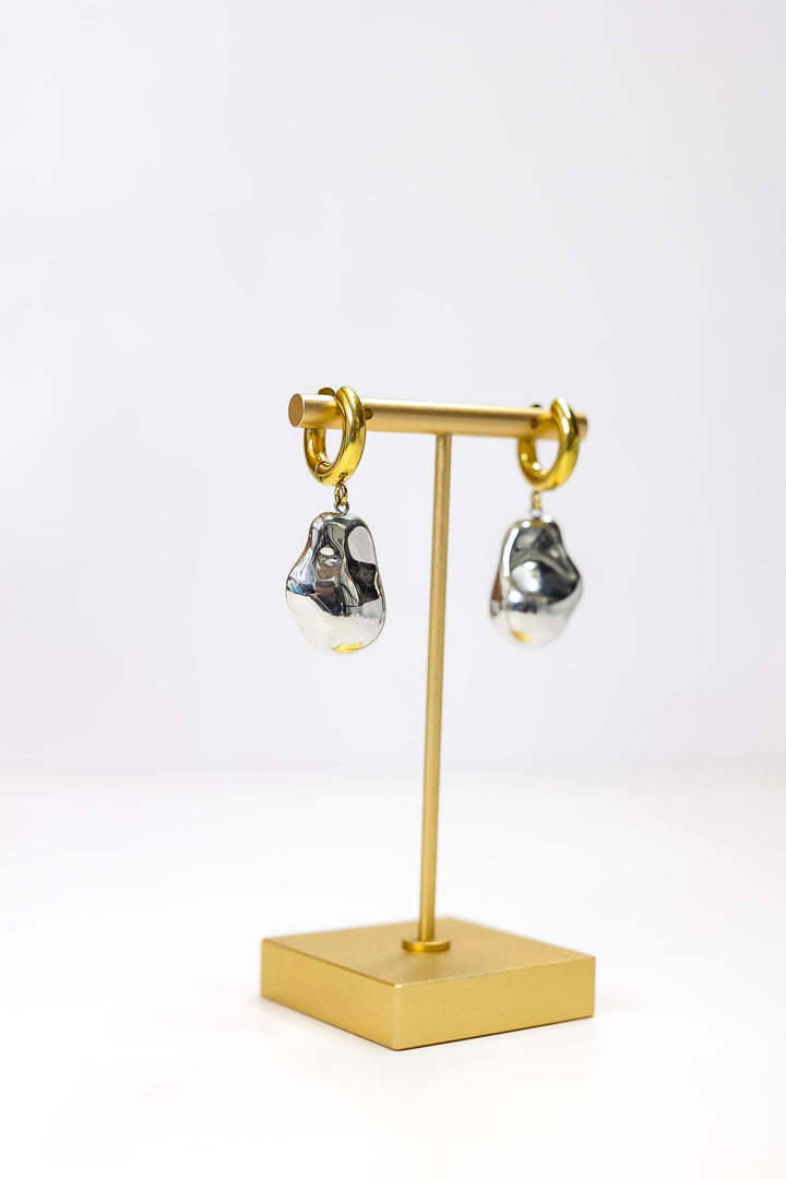 Gold earring stand with silver earrings on a white background