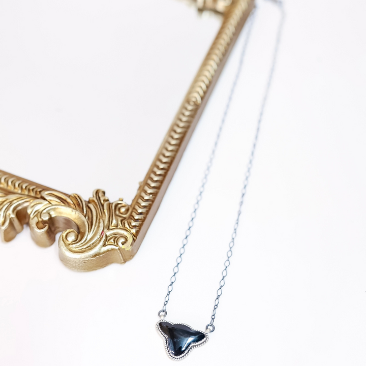 Sterling silver necklace featuring a black onyx cow head silhouette pendant on a 20-inch chain, styled with a vintage gold mirror.