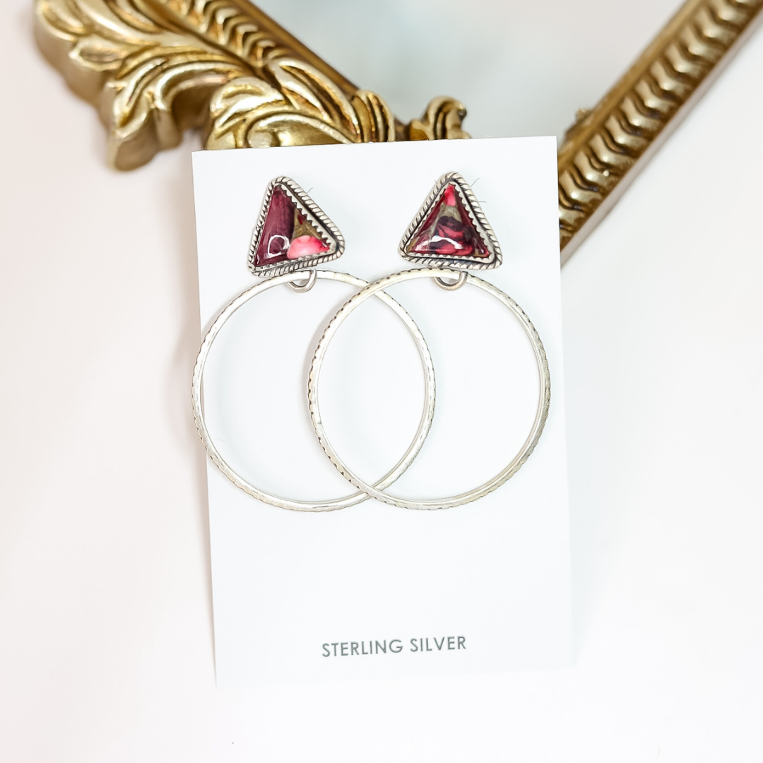Hoop earrings with red gemstone triangles on a white card with 'Sterling Silver' text, gold frame in background