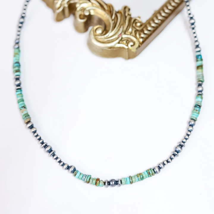 Handmade Red River Turquoise and Sterling Silver Navajo Pearl necklace styled flat with ornate gold frame; 22-inch length with 2-inch extender.