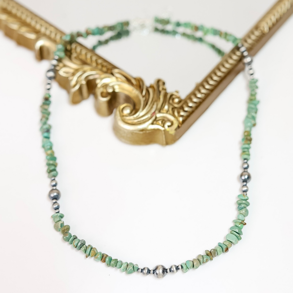 Handmade necklace featuring natural Red River Turquoise chips and sterling silver Navajo pearls, styled on a gold ornate frame with a white background.